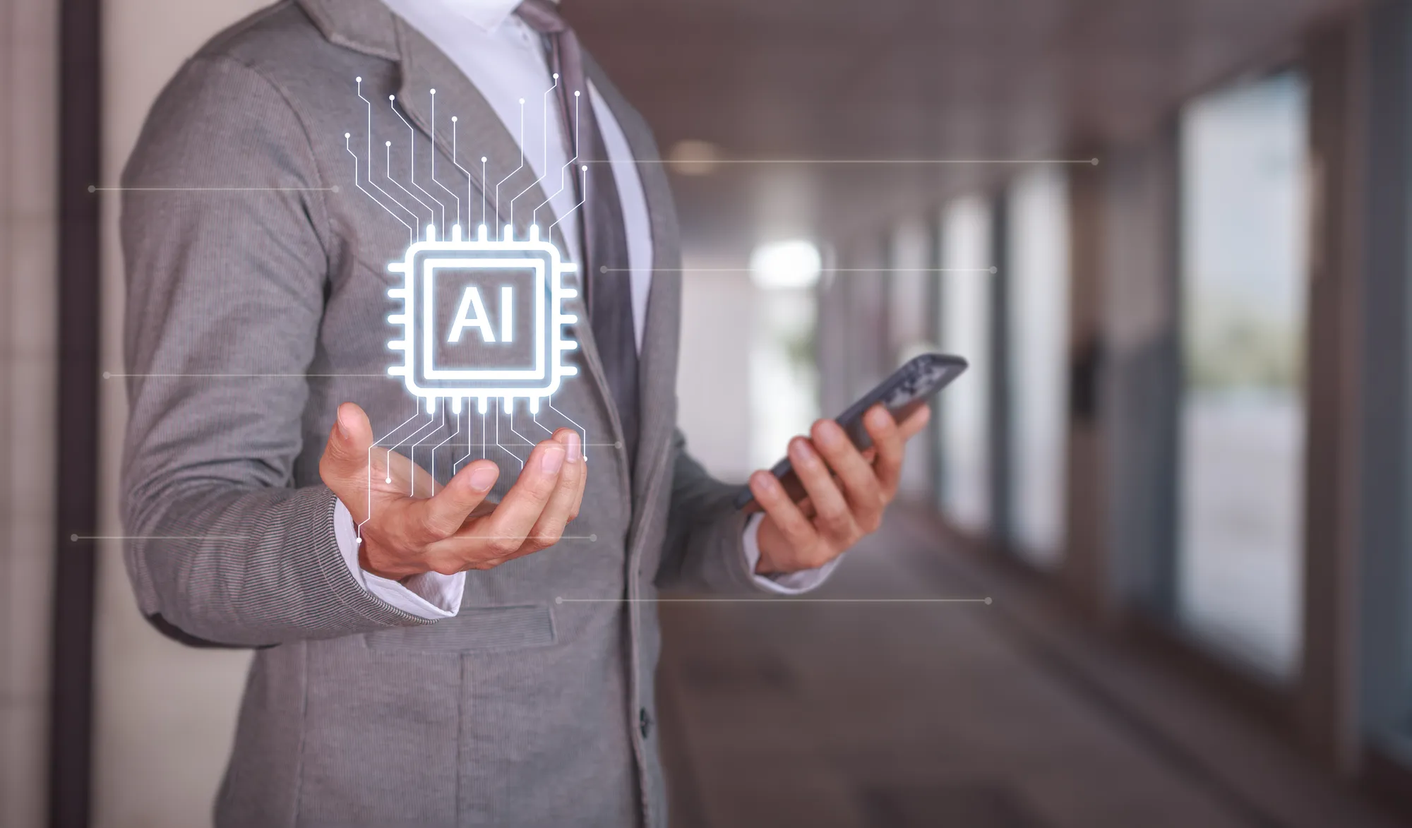 A man wearing a suit and tie holding a cell phone with a AI logo on it.