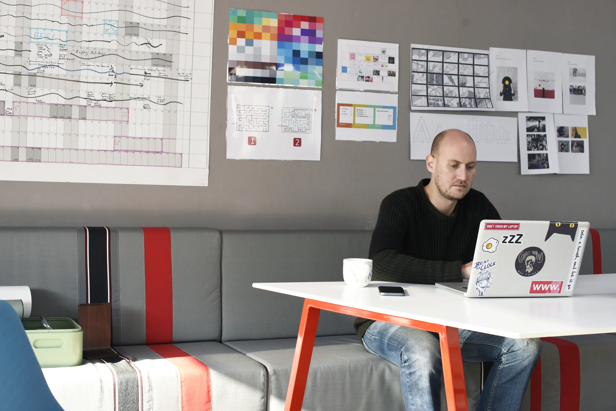A man sitting at a table with a laptop and a cup of coffee.