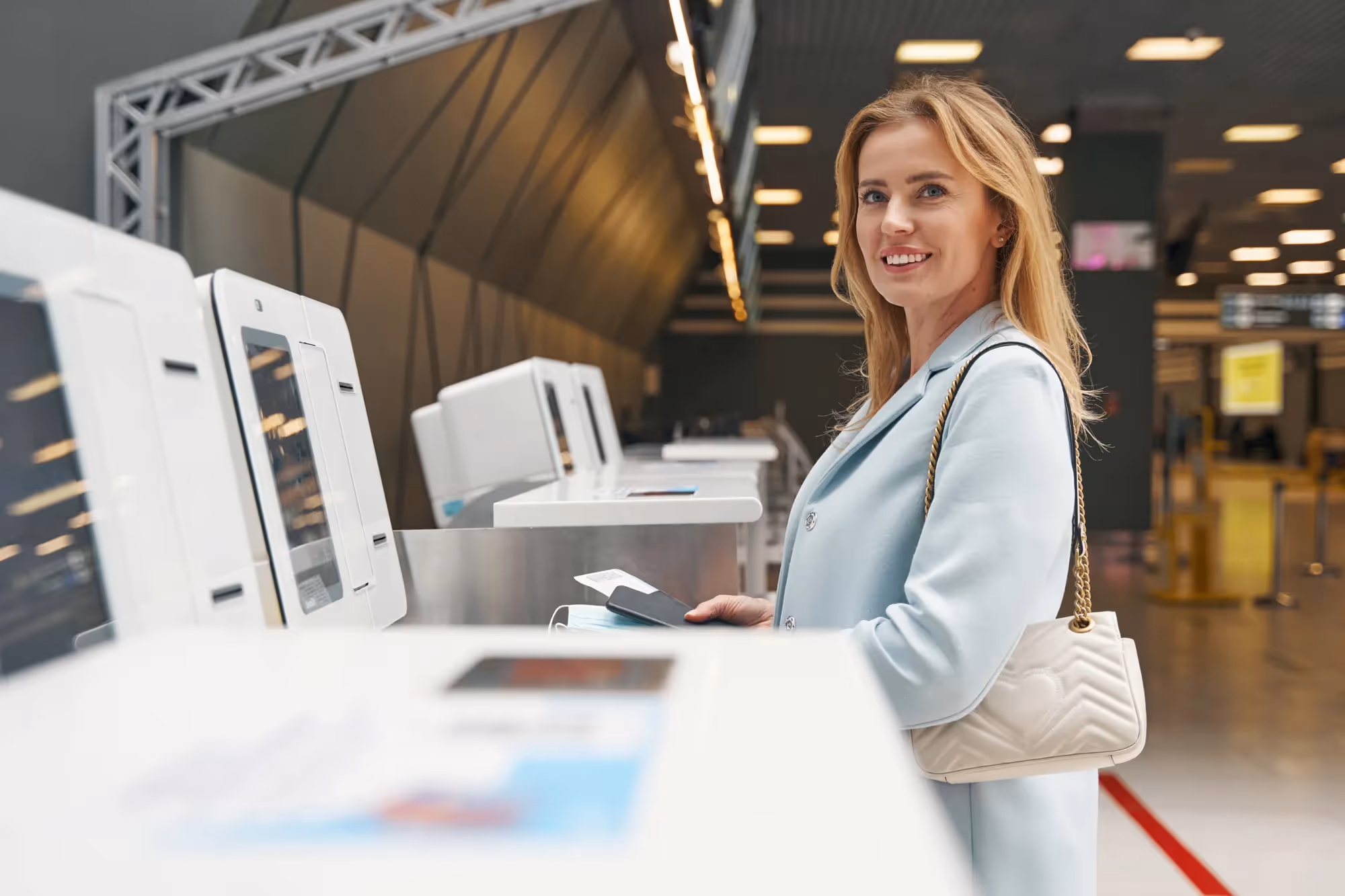 A woman in a blue coat is standing in front of a machine.
