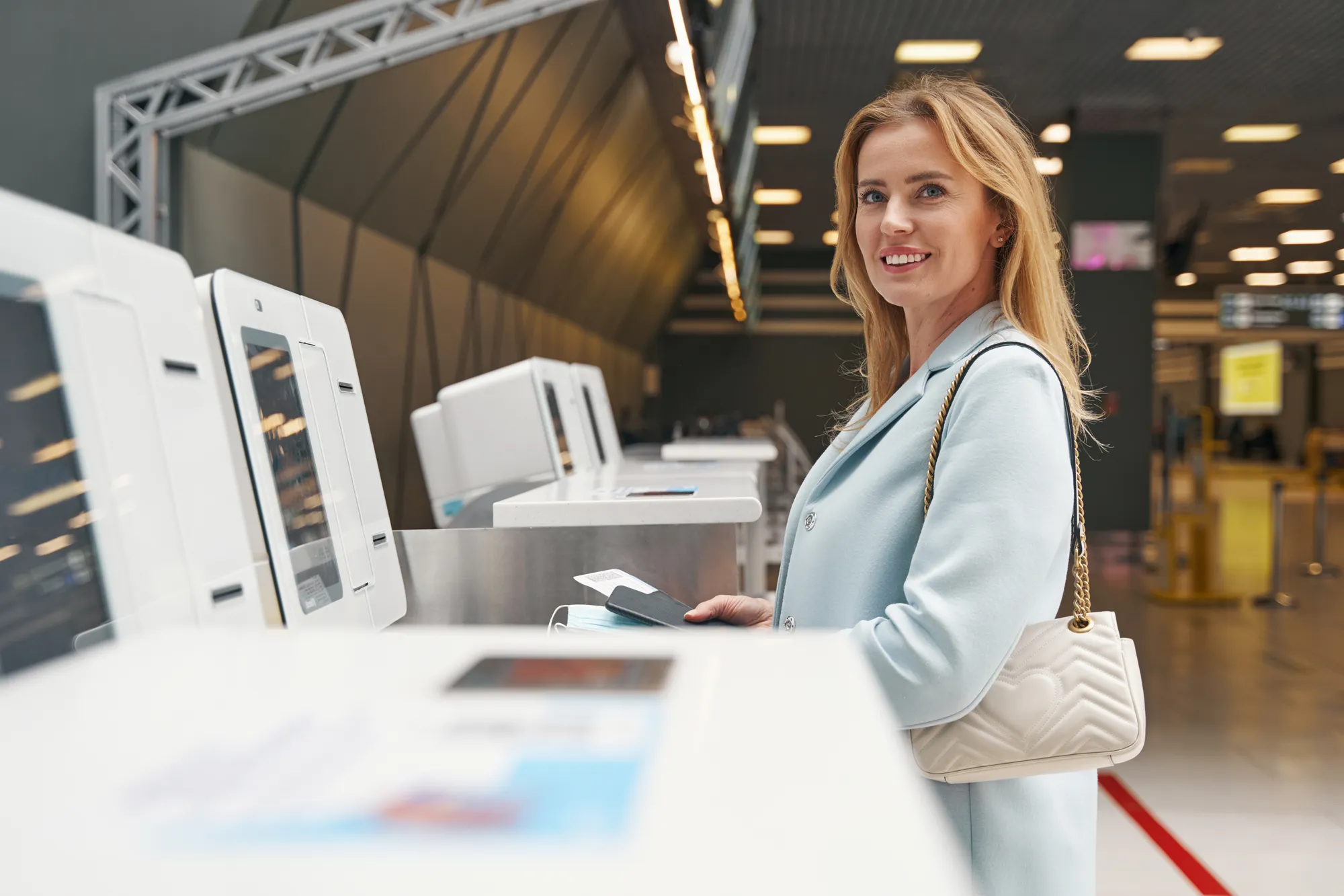 A woman in a blue coat is standing in front of a machine.