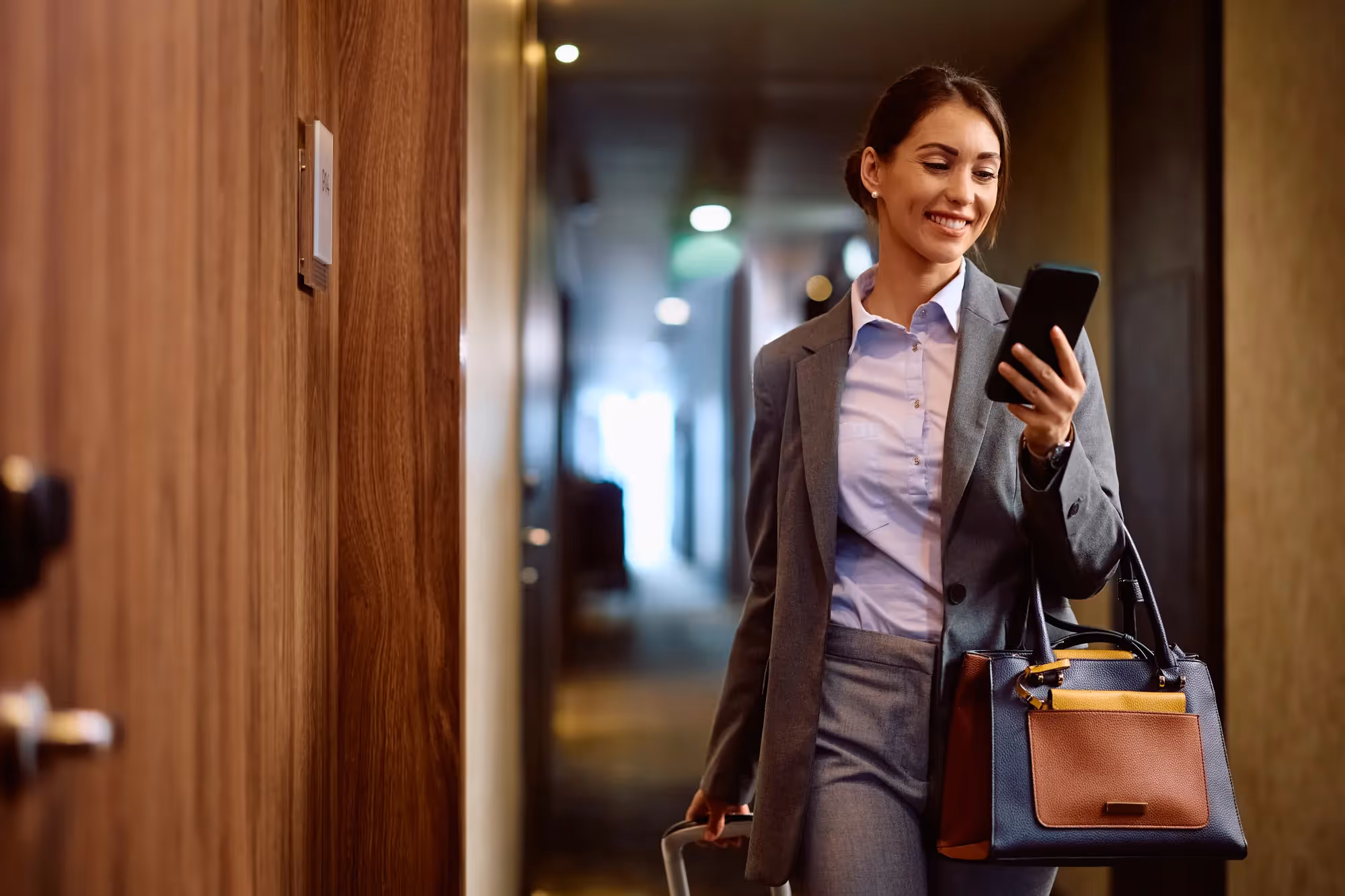 A woman in a grey suit holding a cell phone.