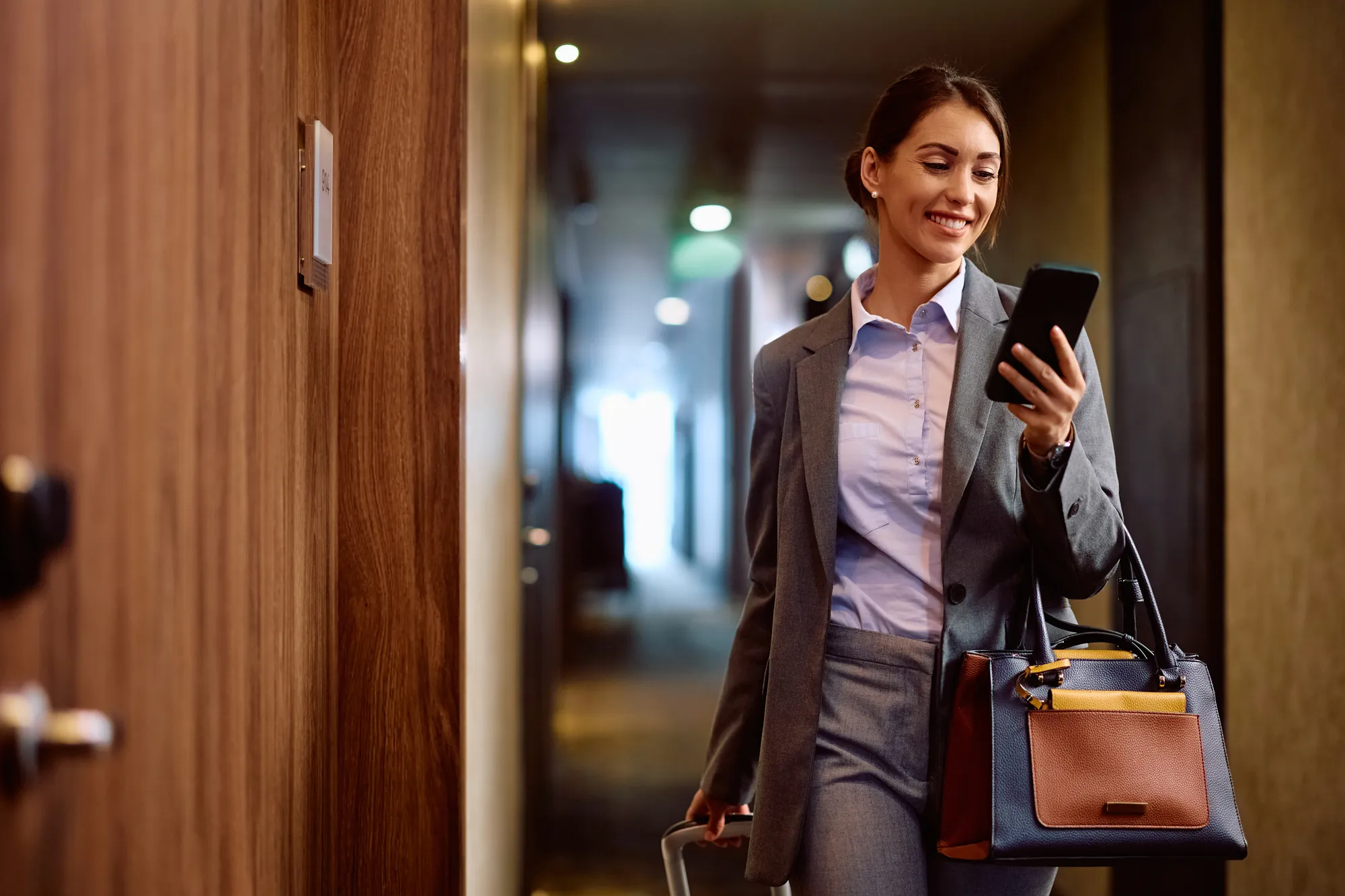 A woman in a grey suit holding a cell phone.