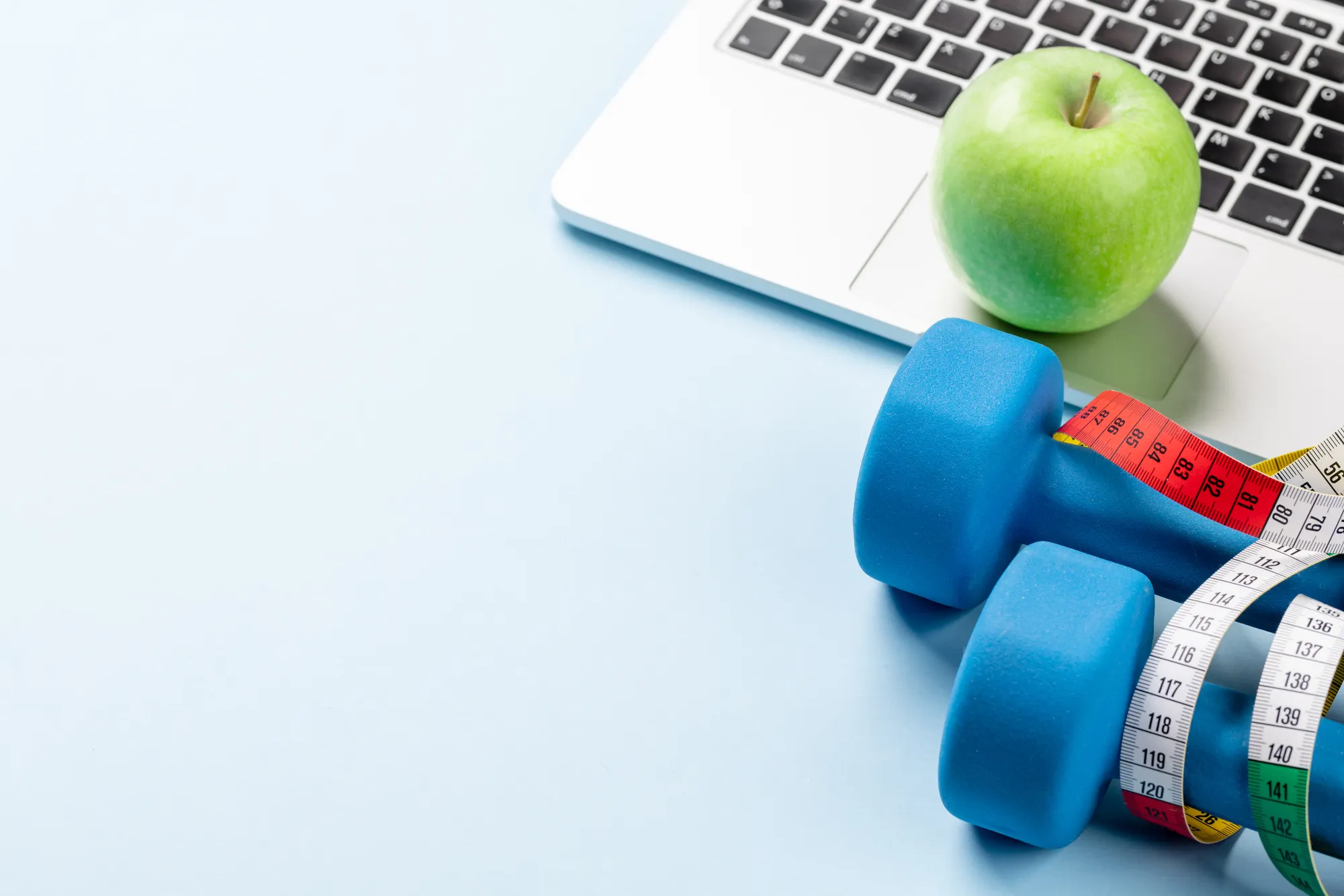 A blue exercise wheel with a yellow apple and a laptop computer.