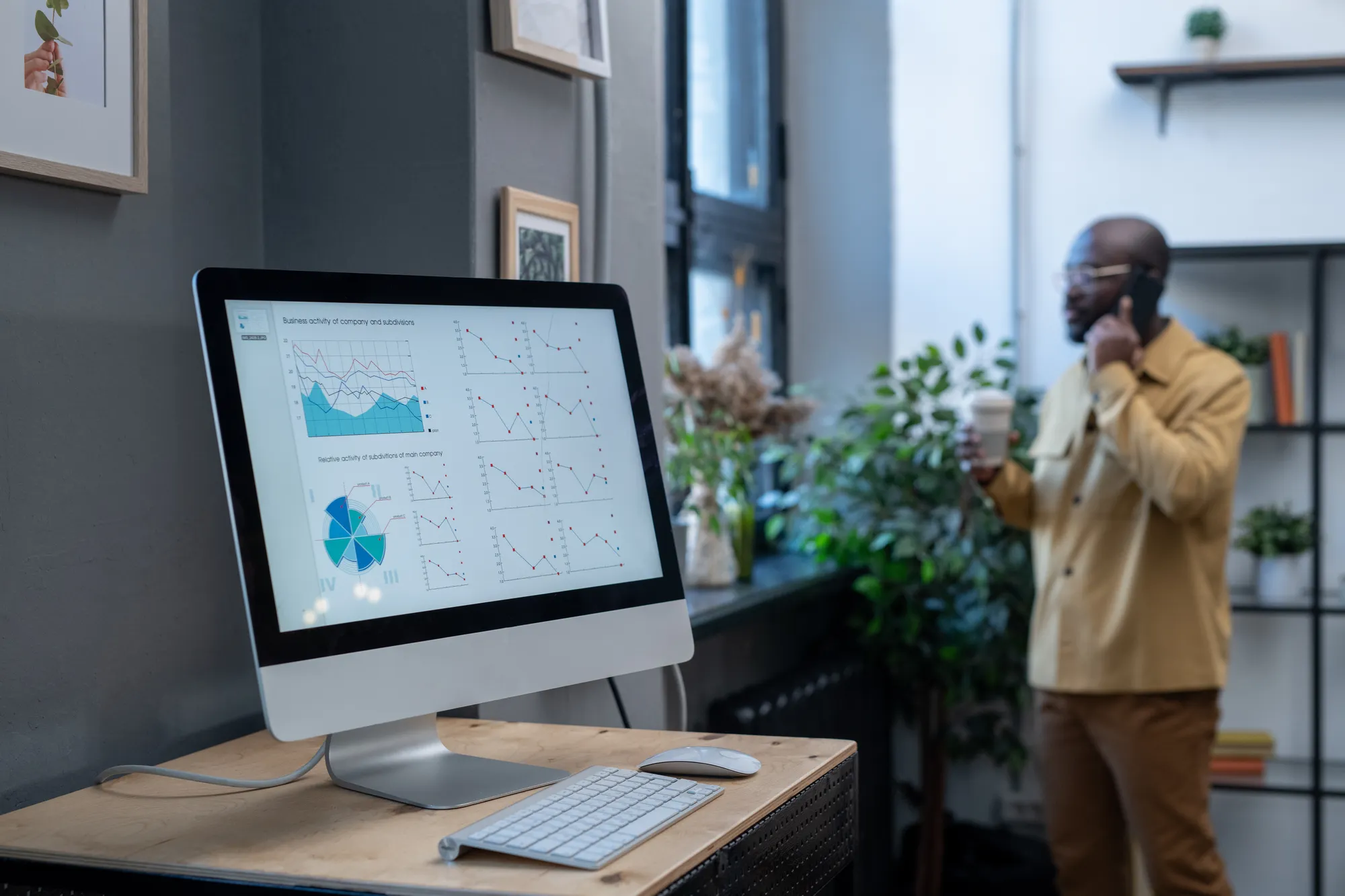 A man standing in front of a computer screen with graphs on it.