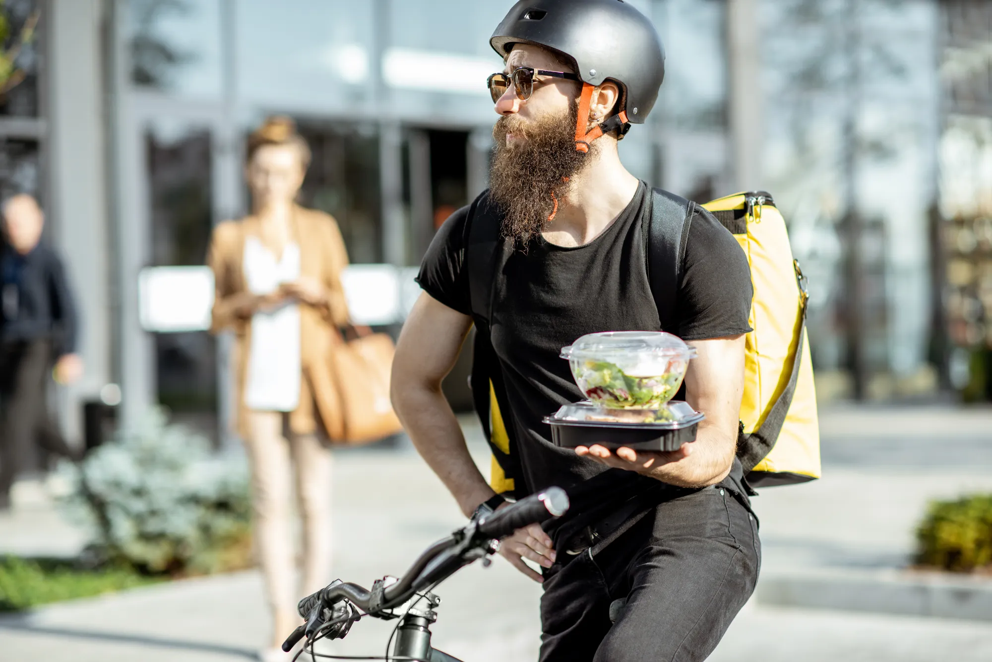 A man with a beard and a black shirt holding a tray of food.