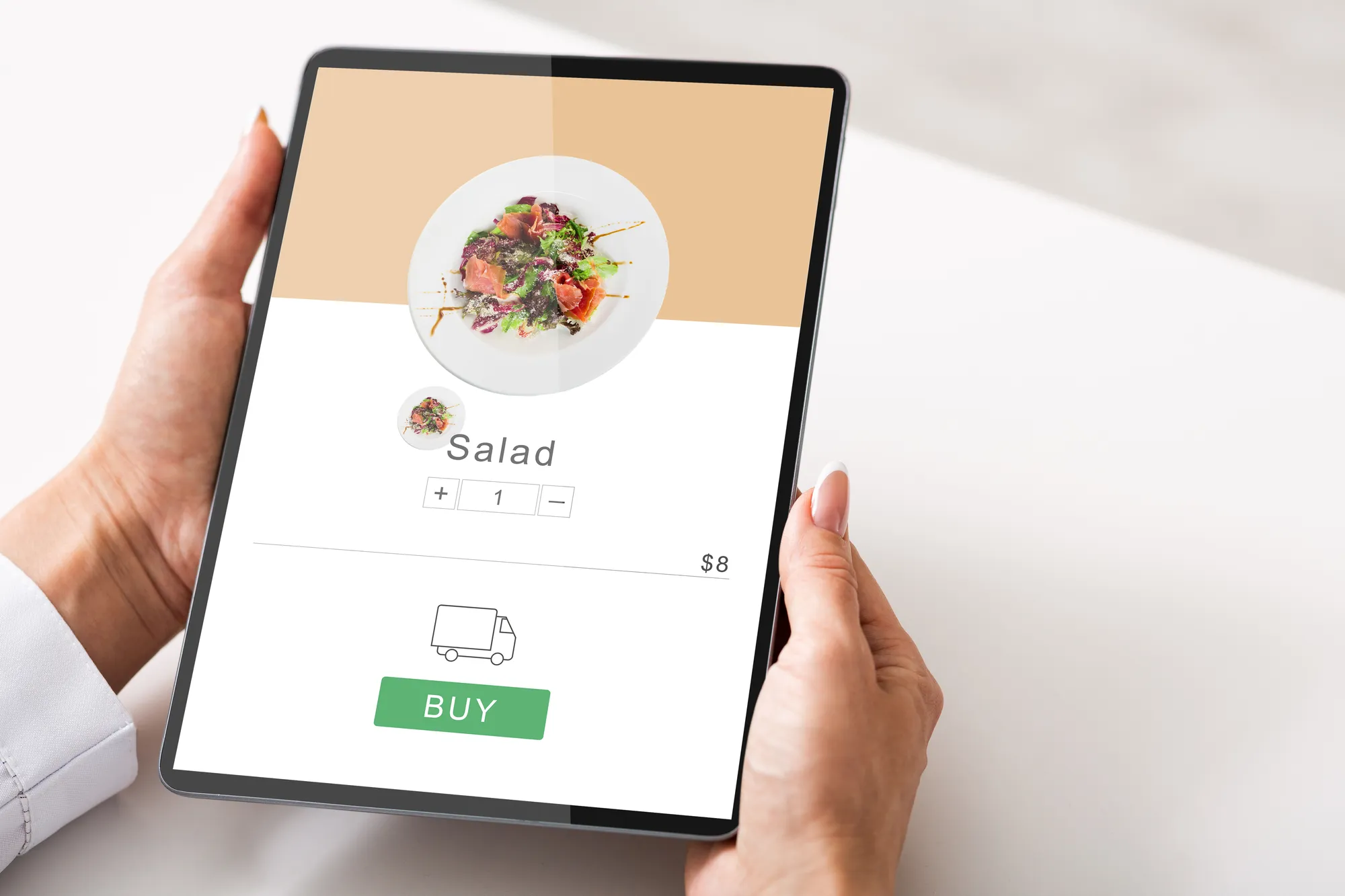 A hand holding a tablet with a salad on the screen.