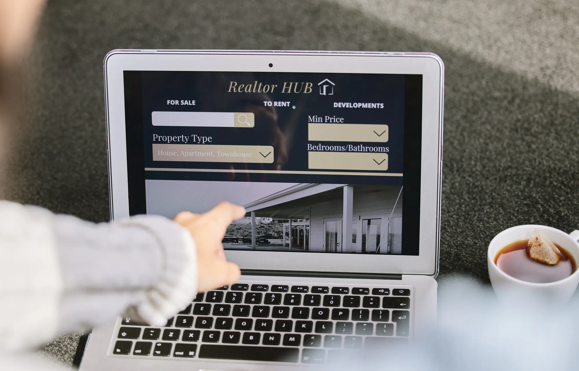 A person is using a laptop to look at a website for a real estate company.