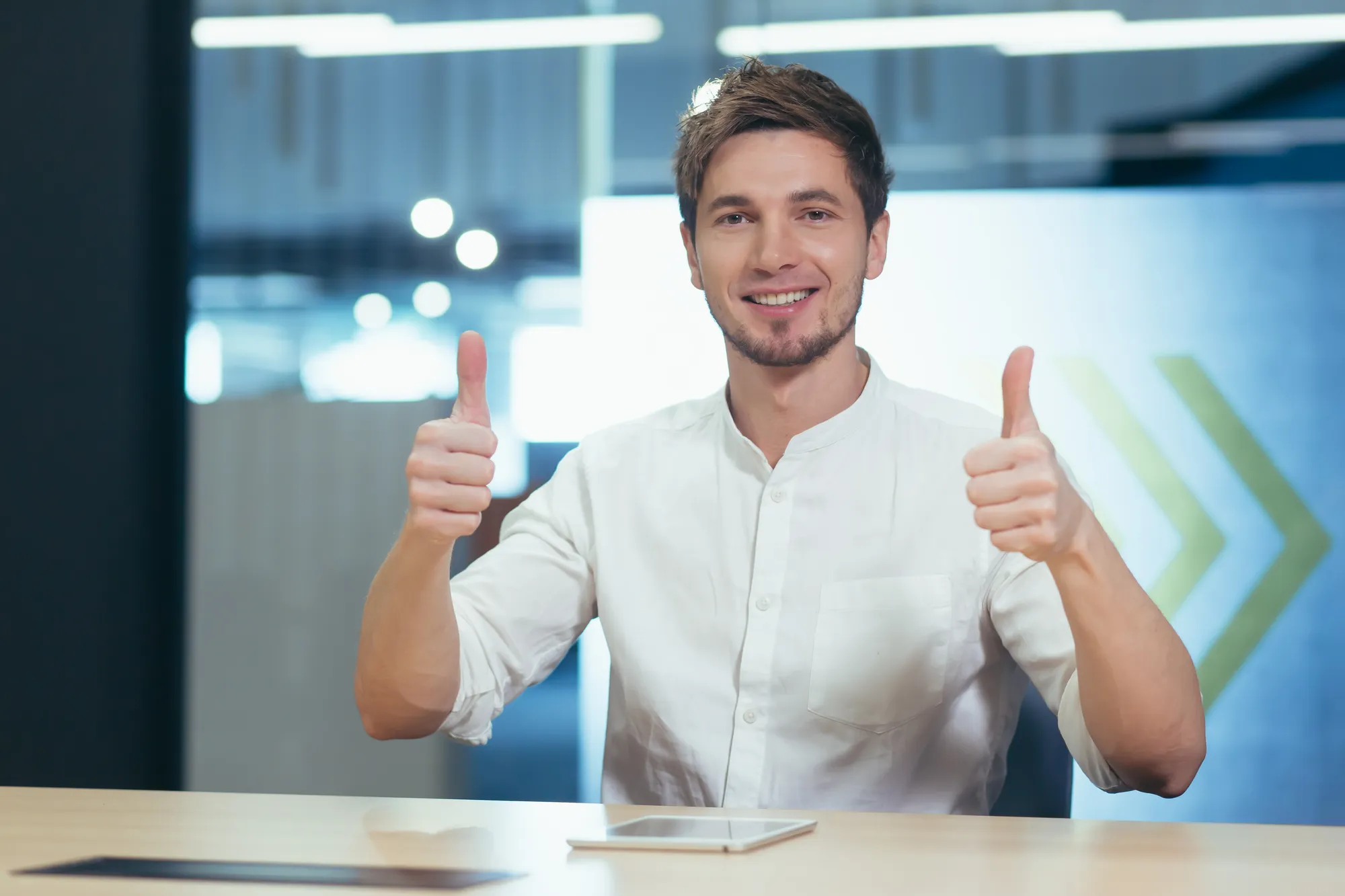 A man giving a thumbs up in front of a table.