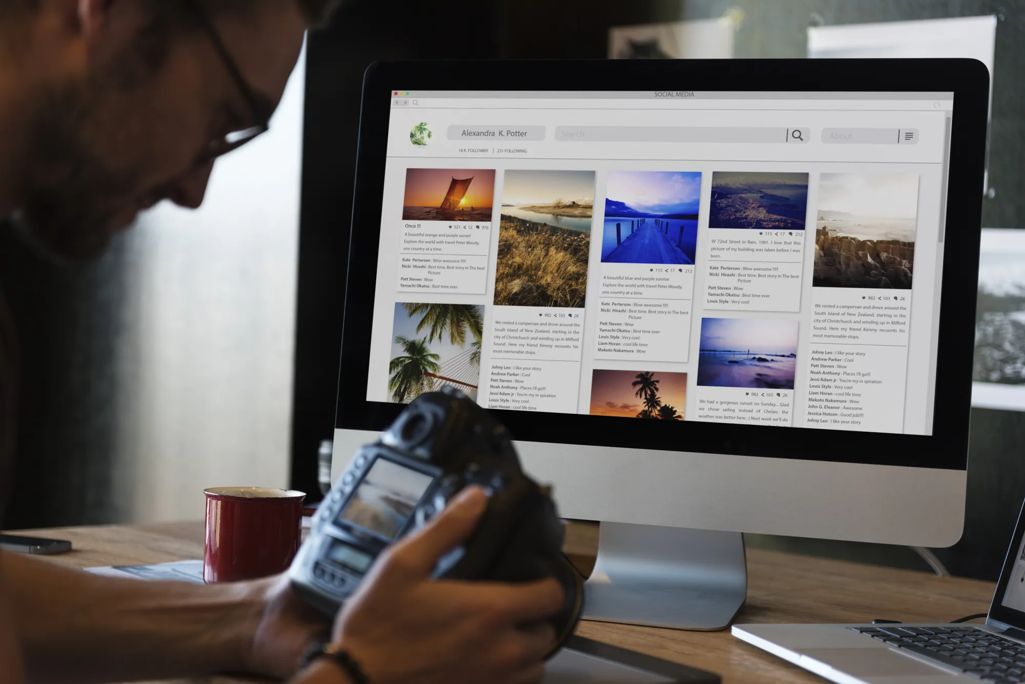 A man is holding a camera and looking at a computer screen.