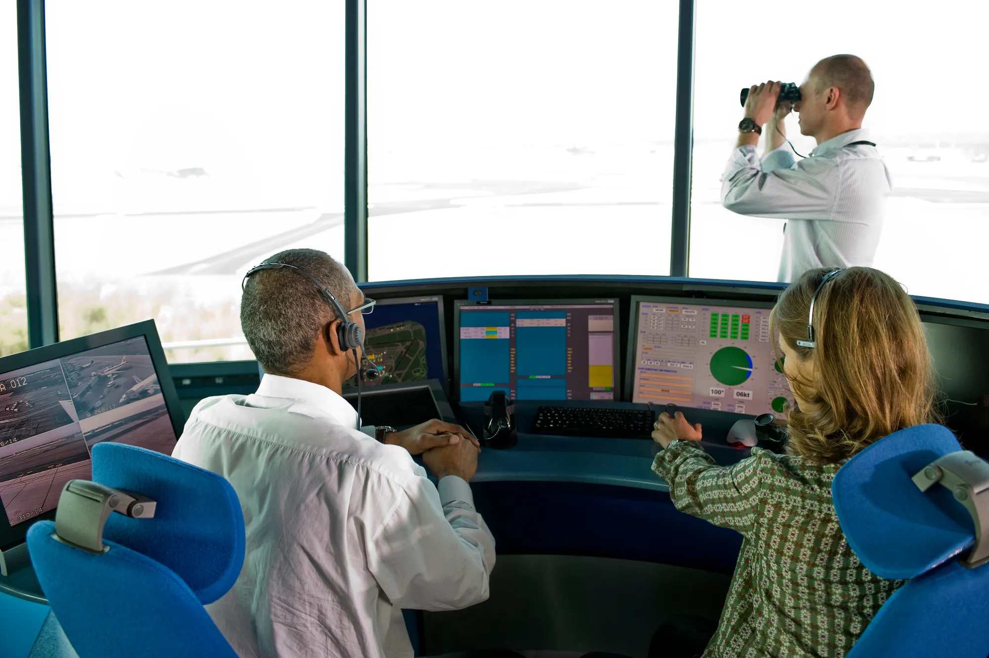 A man and woman are sitting in front of a control panel.