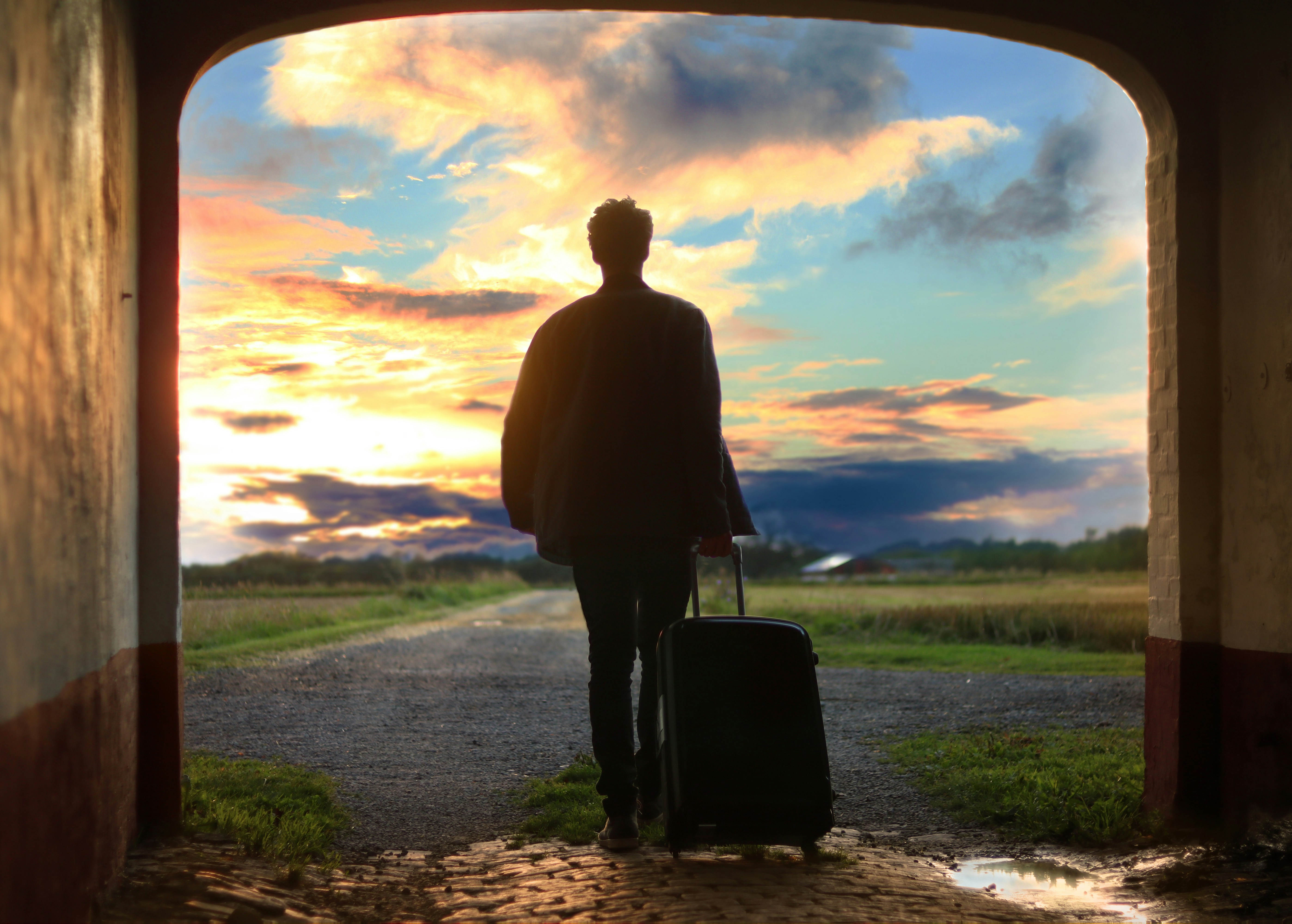 A man walking down a road with a suitcase.