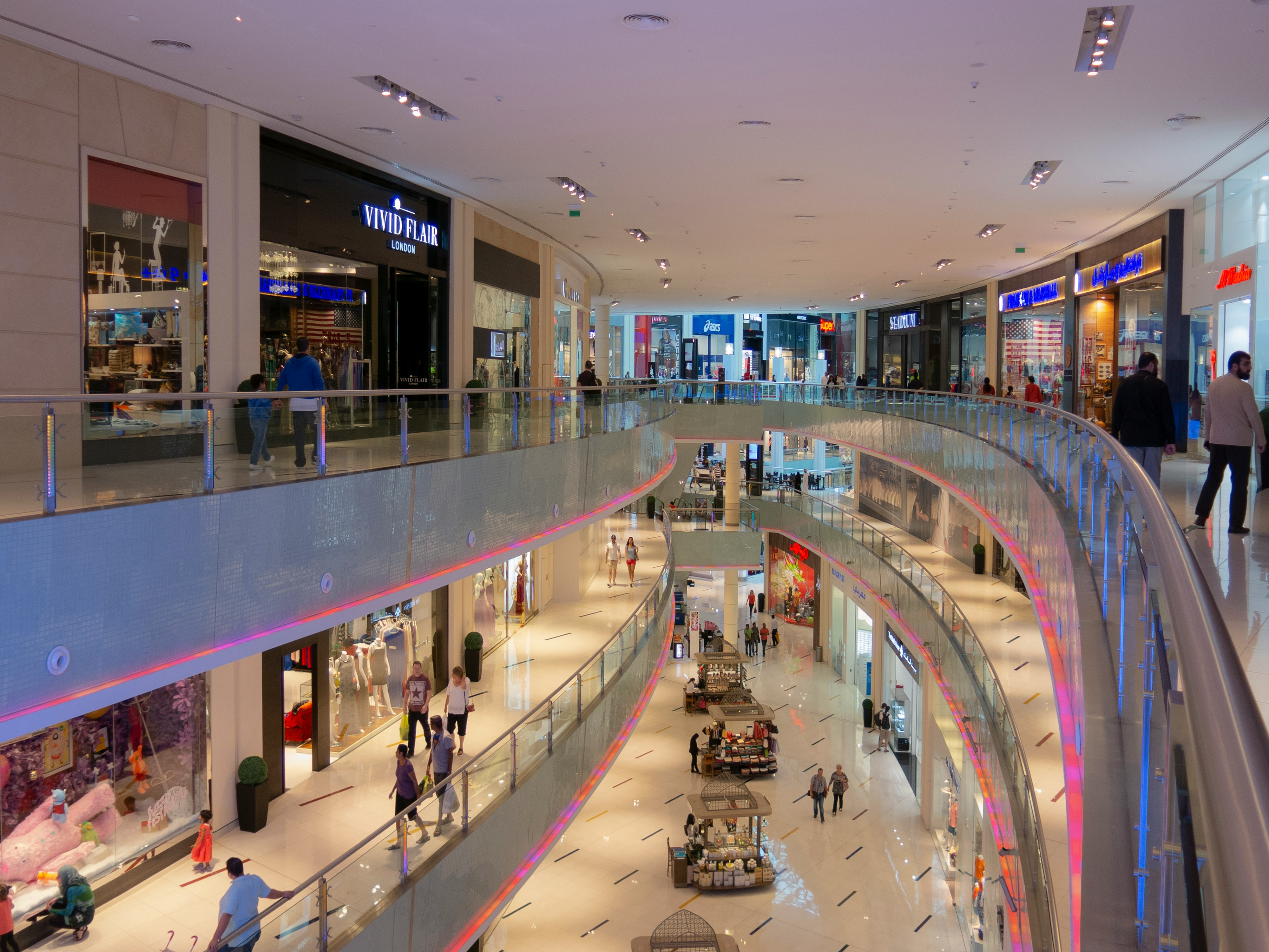 A large mall with a glass ceiling and a spiral staircase.
