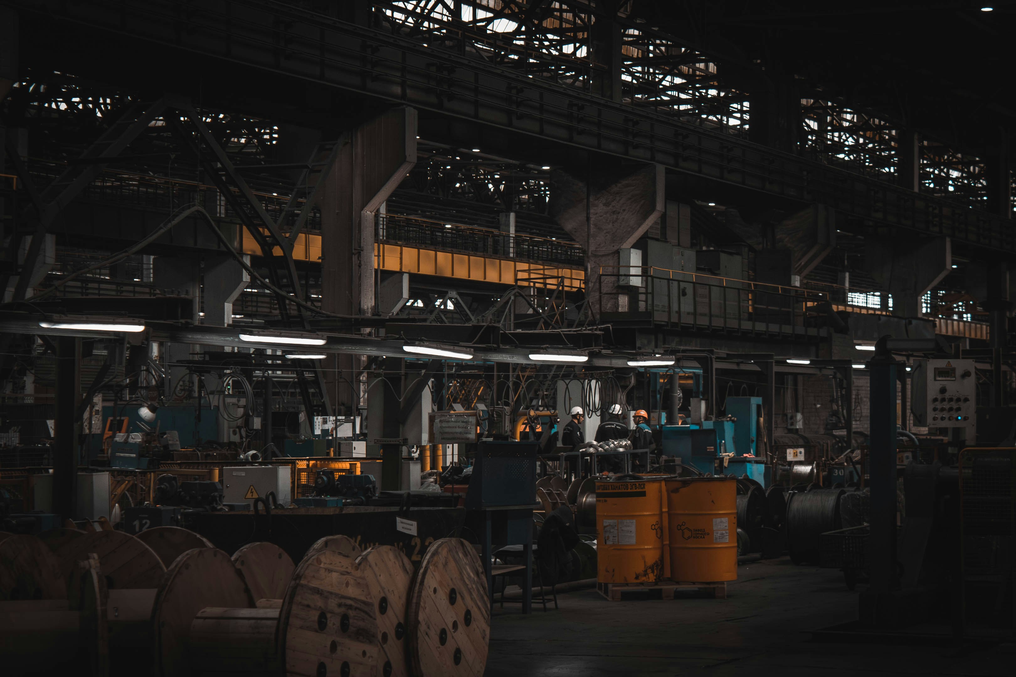 A factory with a large metal structure and a man in a hard hat.
