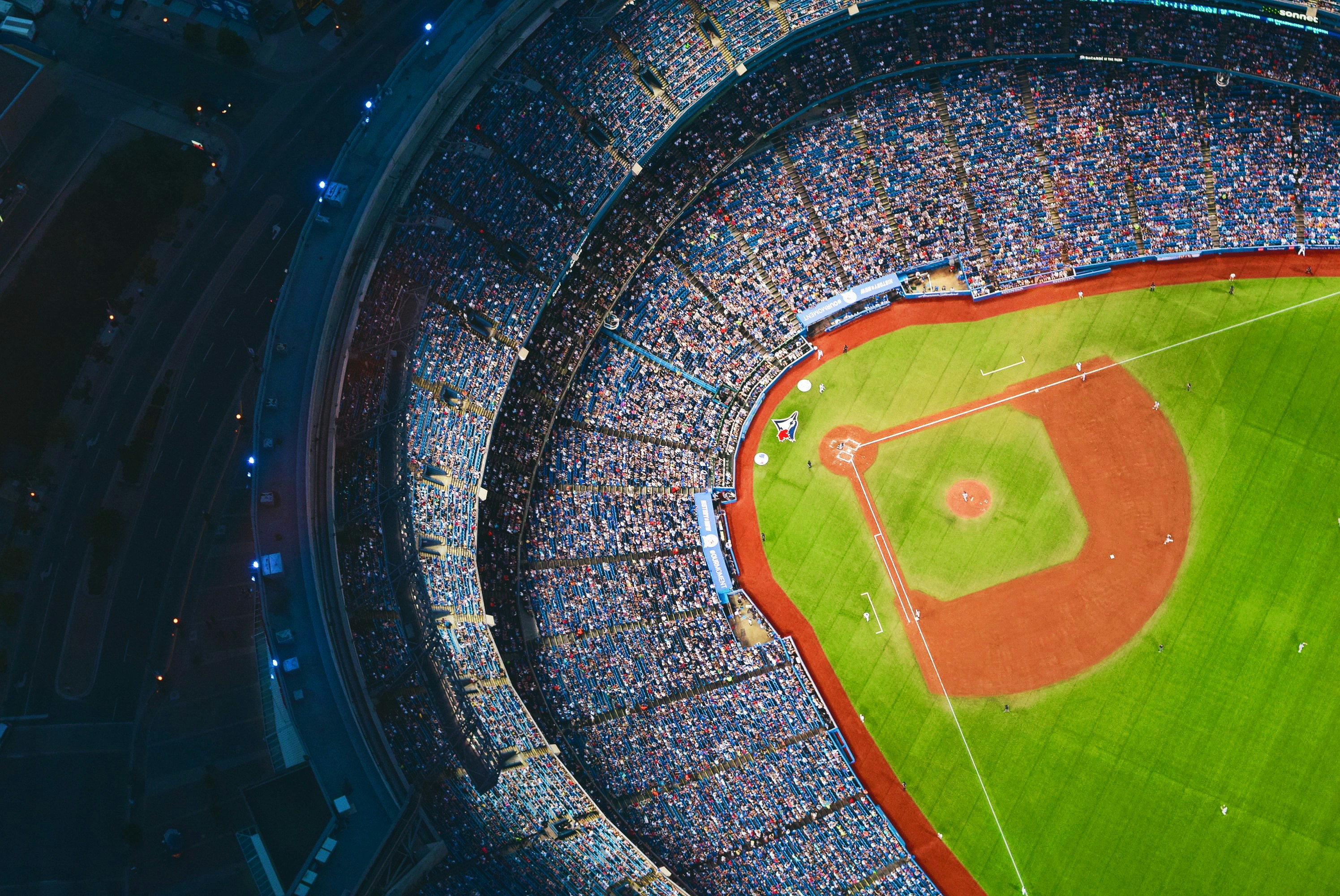 A baseball stadium with a green field and a large crowd of people.