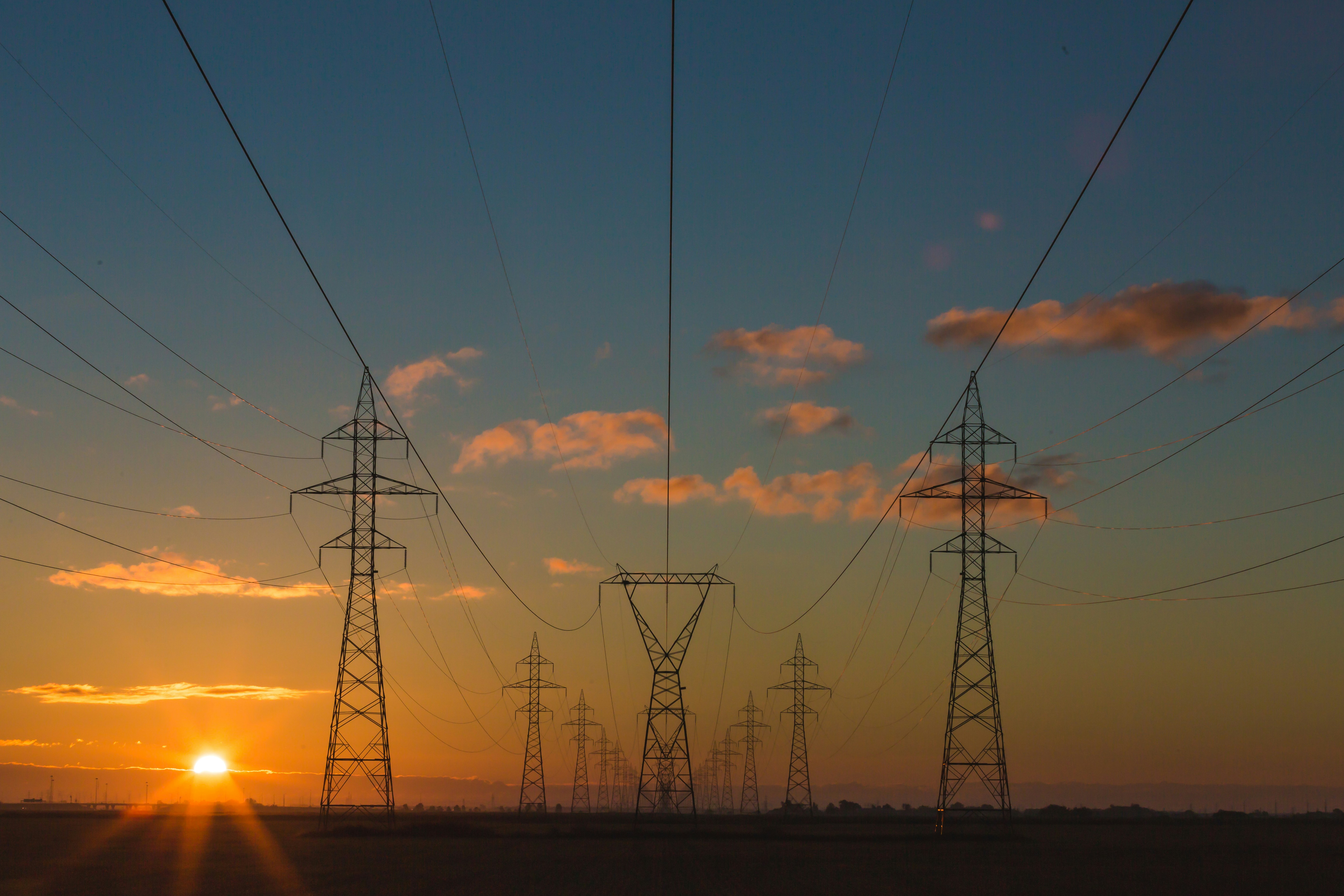 A sunset with power lines and a cloudy sky.
