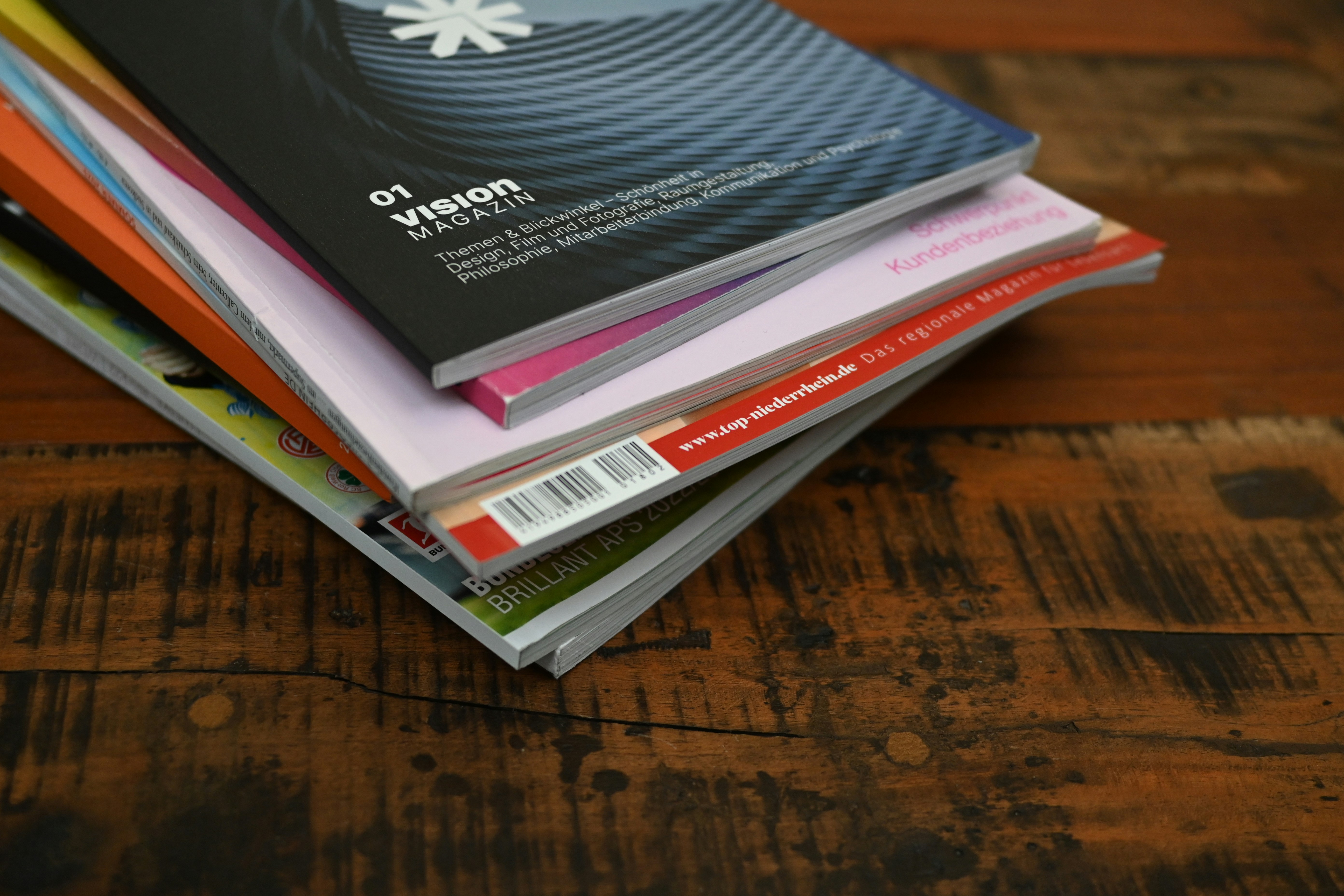 A stack of magazines on a table with one of them titled Vision.