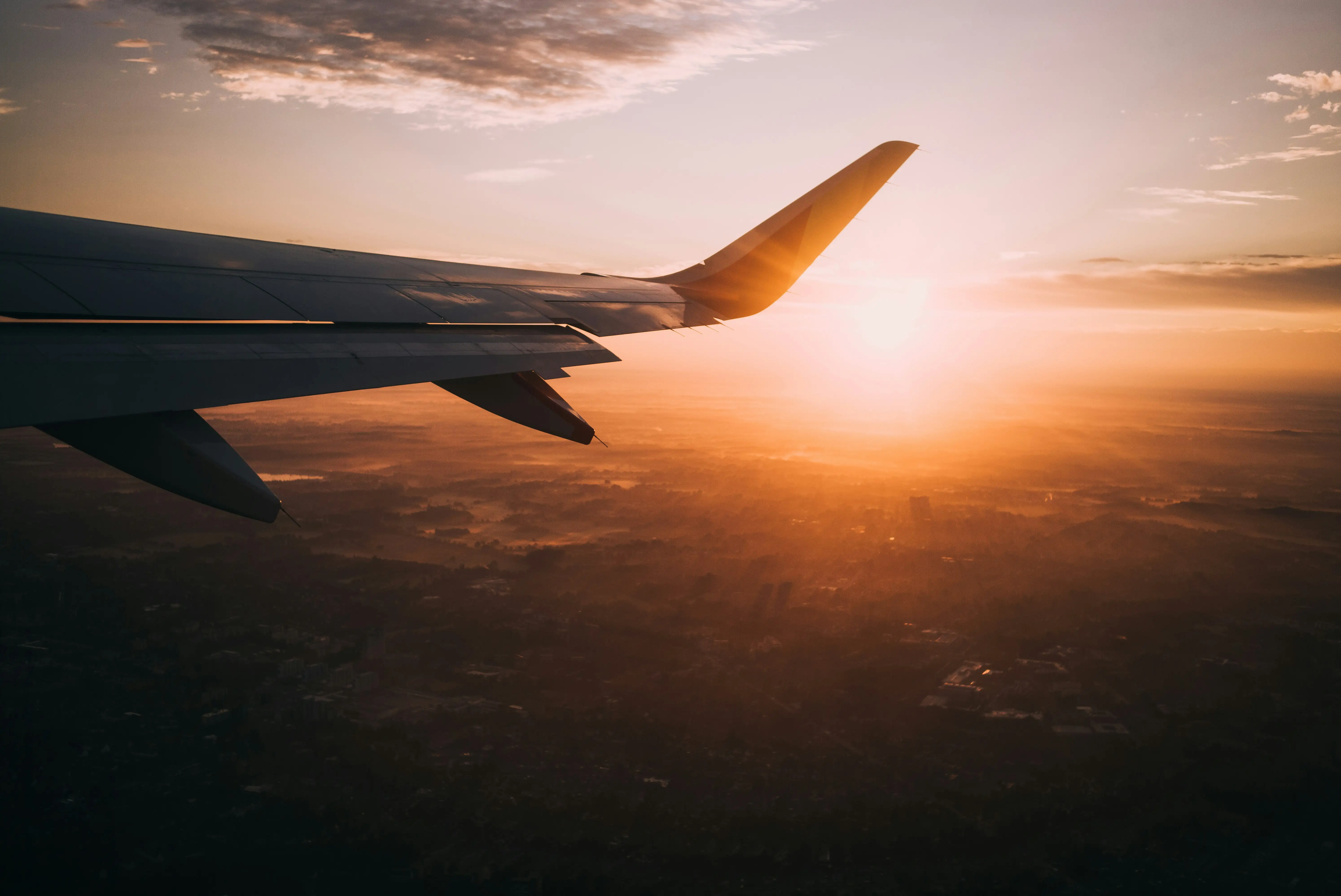 A plane wing with the sun shining on it.