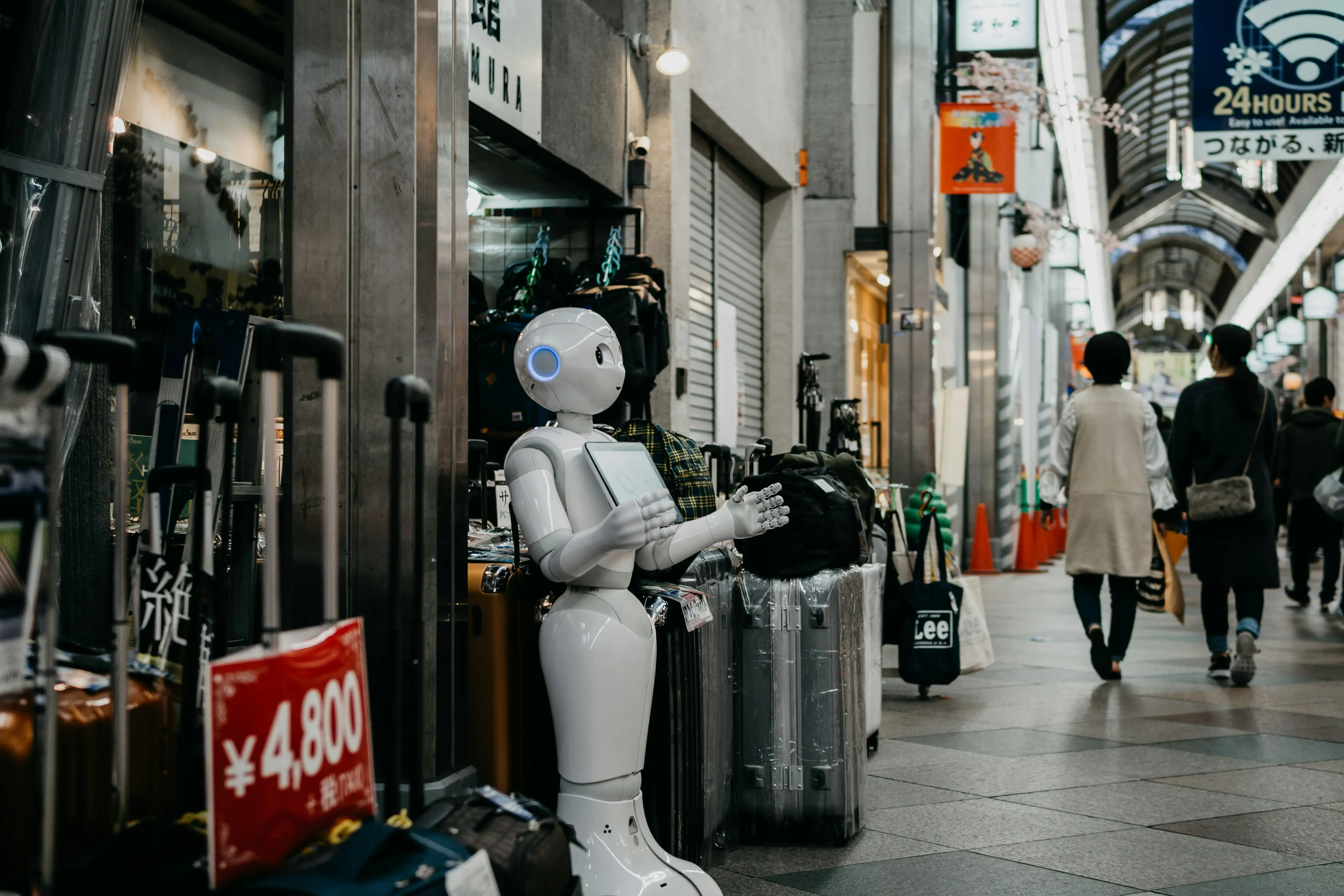 A robot is standing in front of a suitcase.