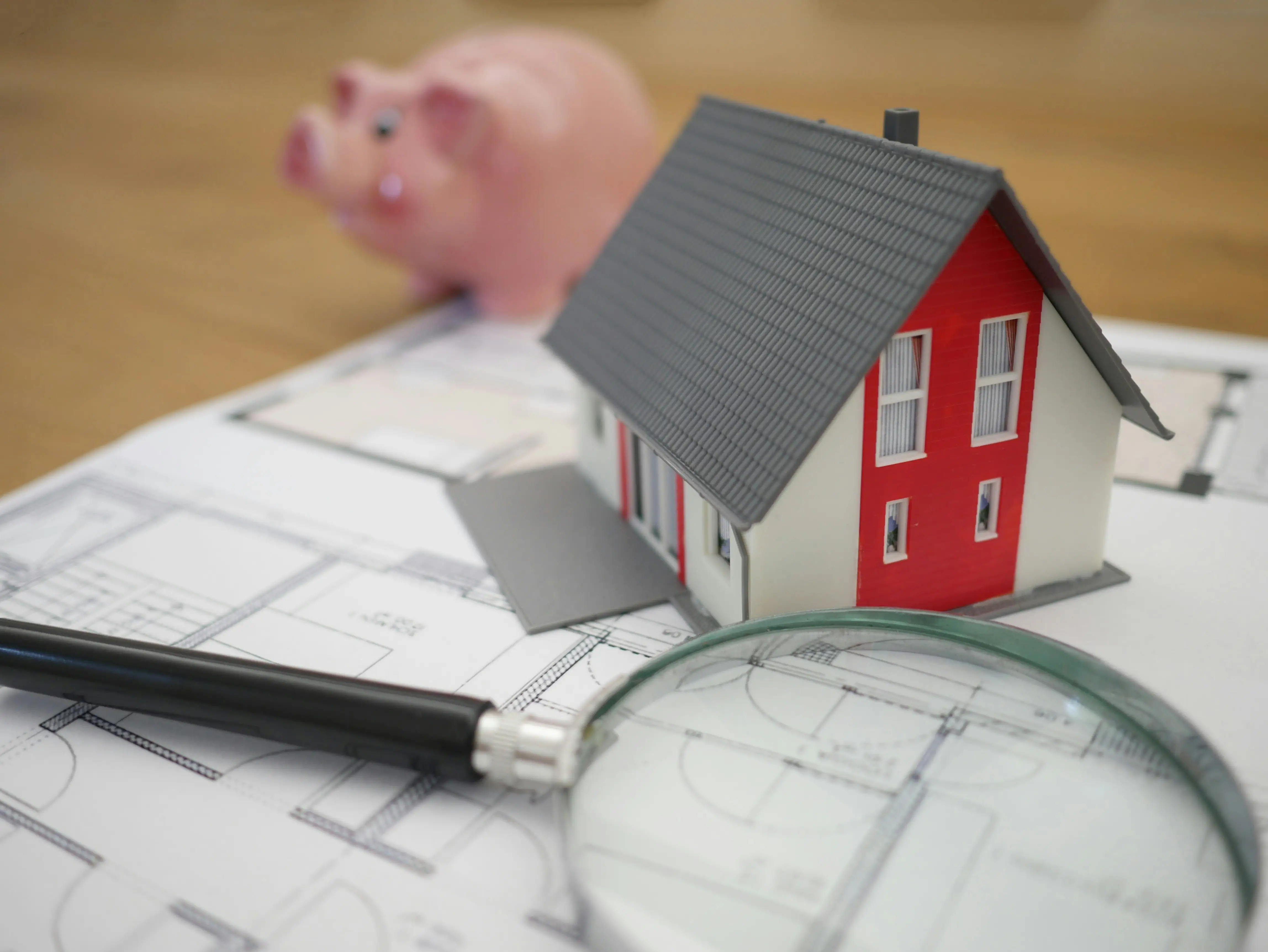 A piggy bank and a house plan are on a table.