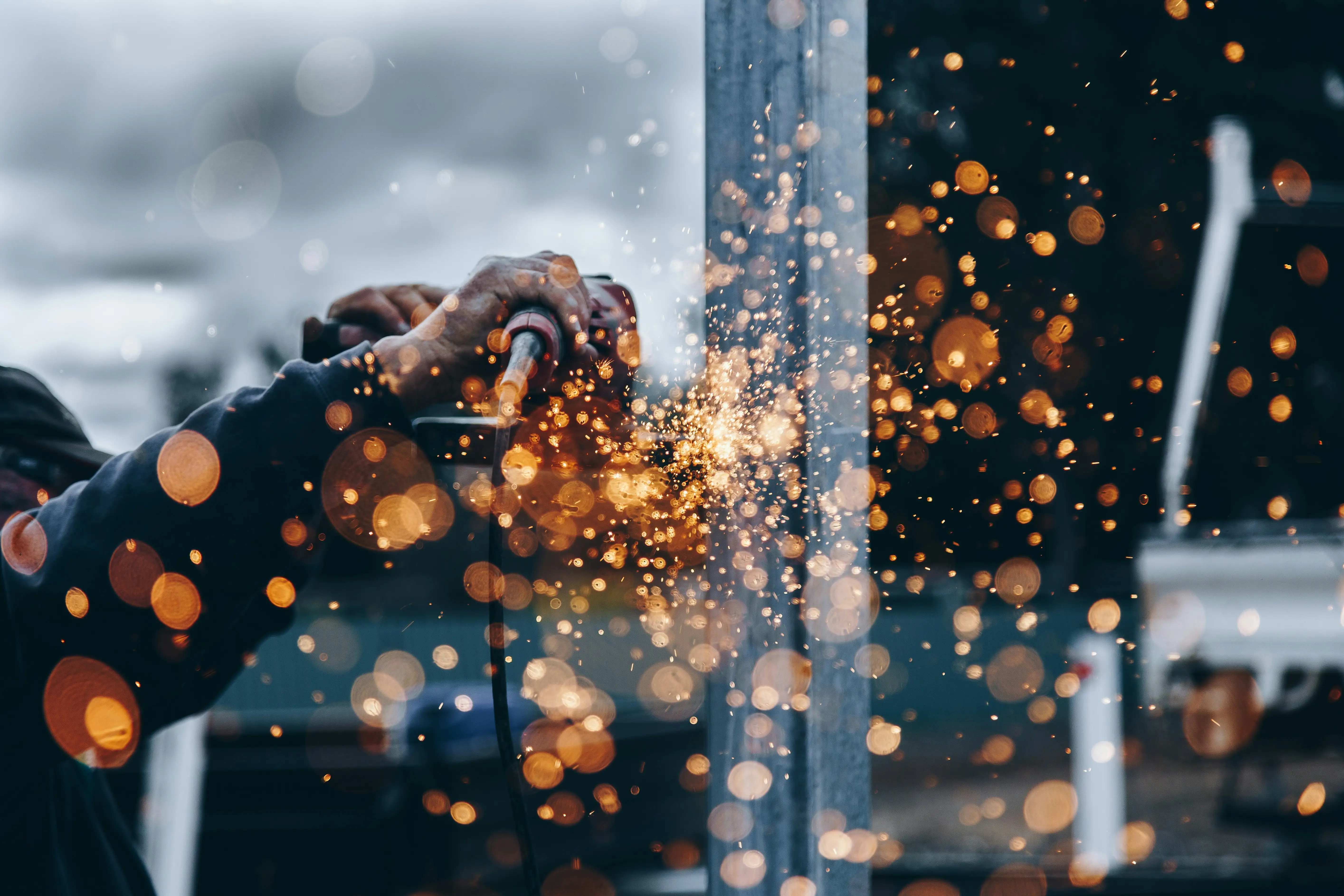 A person is using a sparkler to cut a metal pipe.