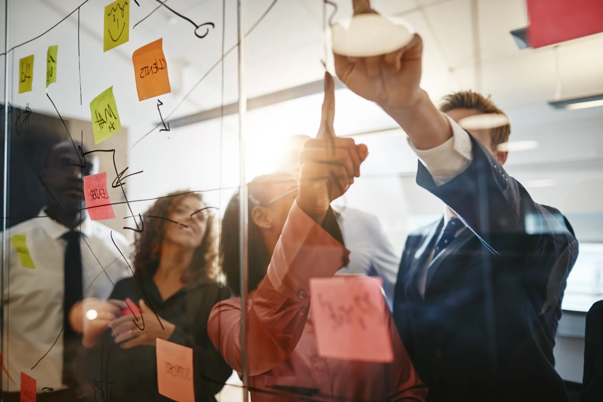 A group of people looking at a white board with sticky notes on it.