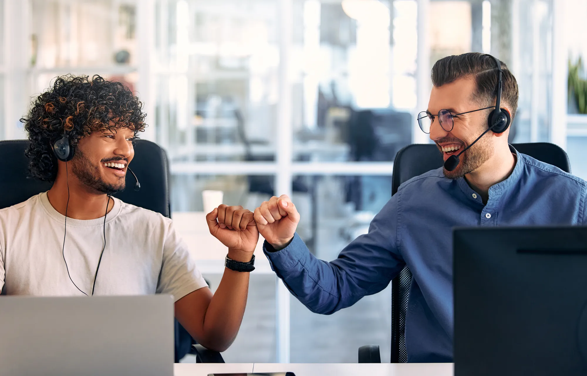 Two men shake hands in front of a computer.