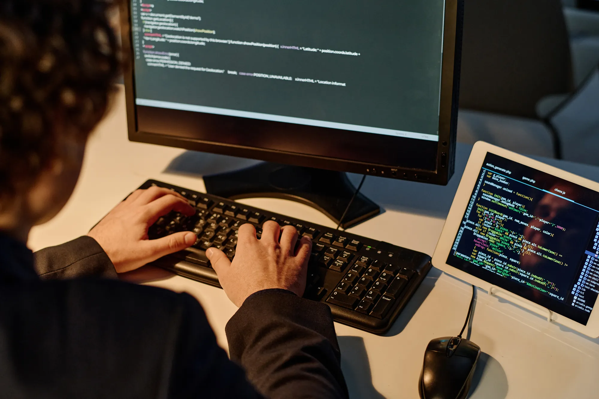 A man is typing on a computer with a mouse and keyboard in front of him.