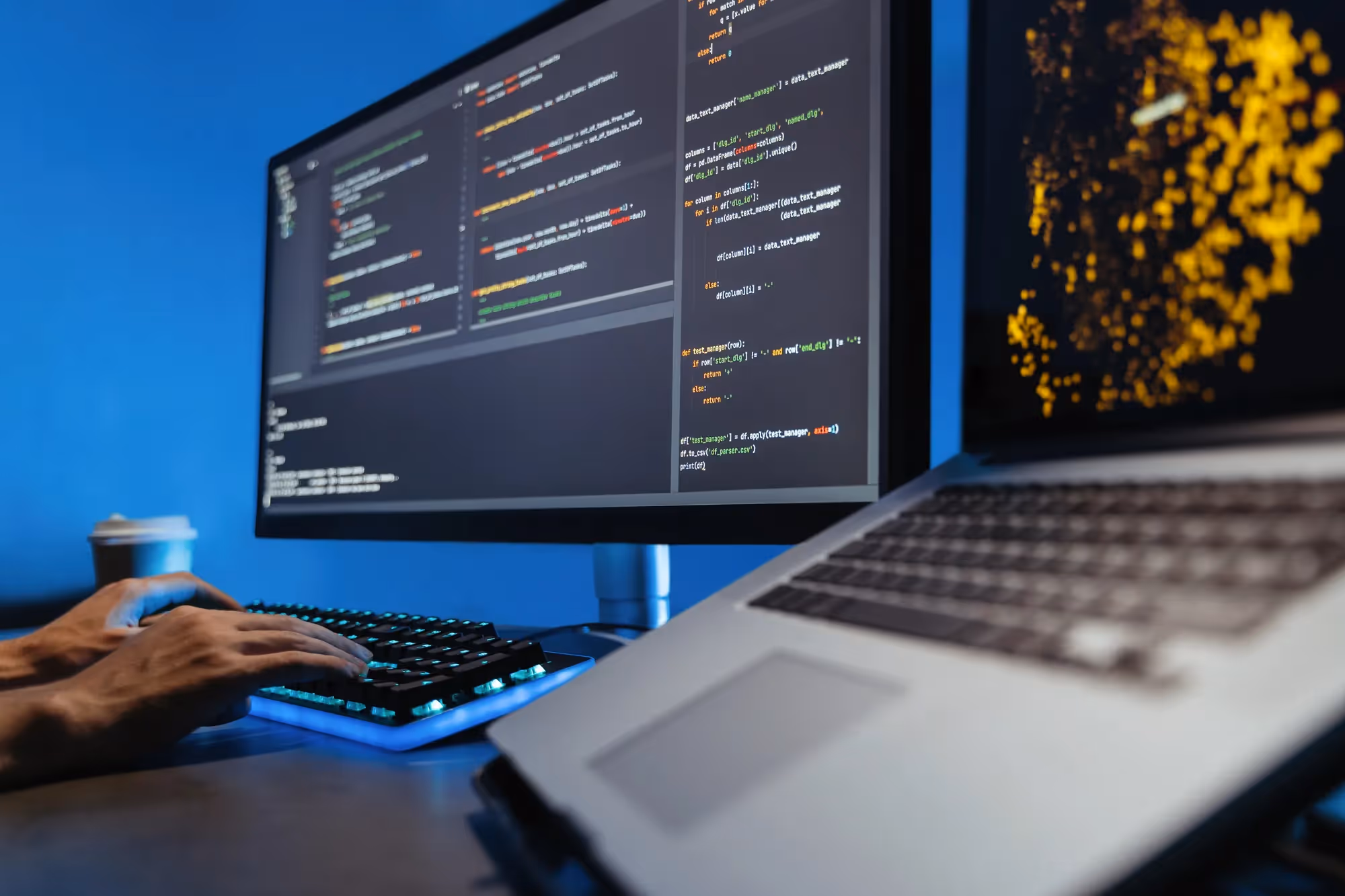 A laptop with a keyboard and a monitor displaying code.