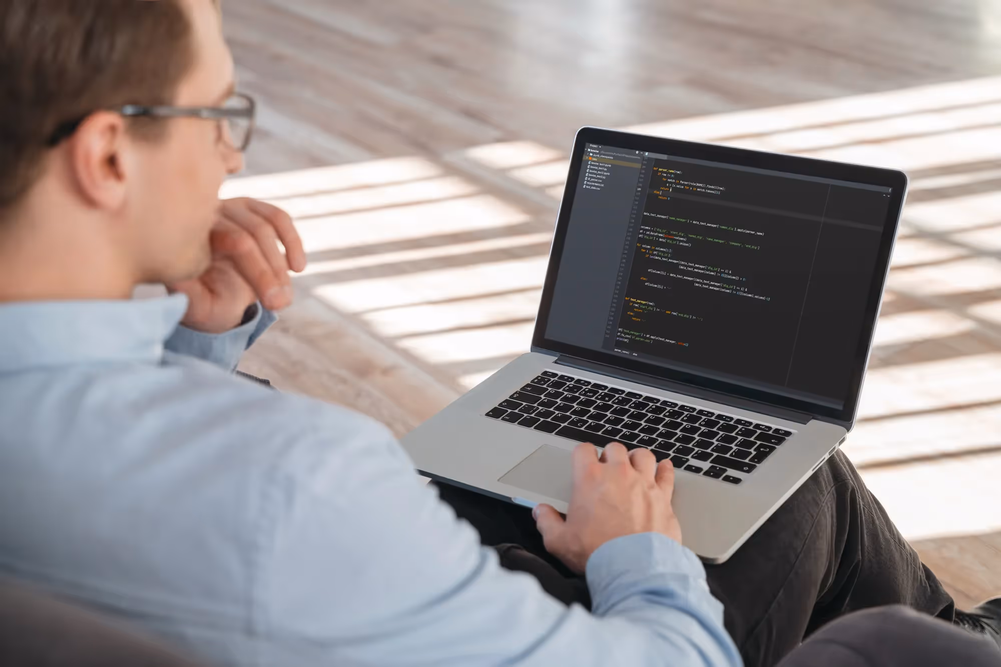 A man wearing glasses is sitting in front of a laptop.