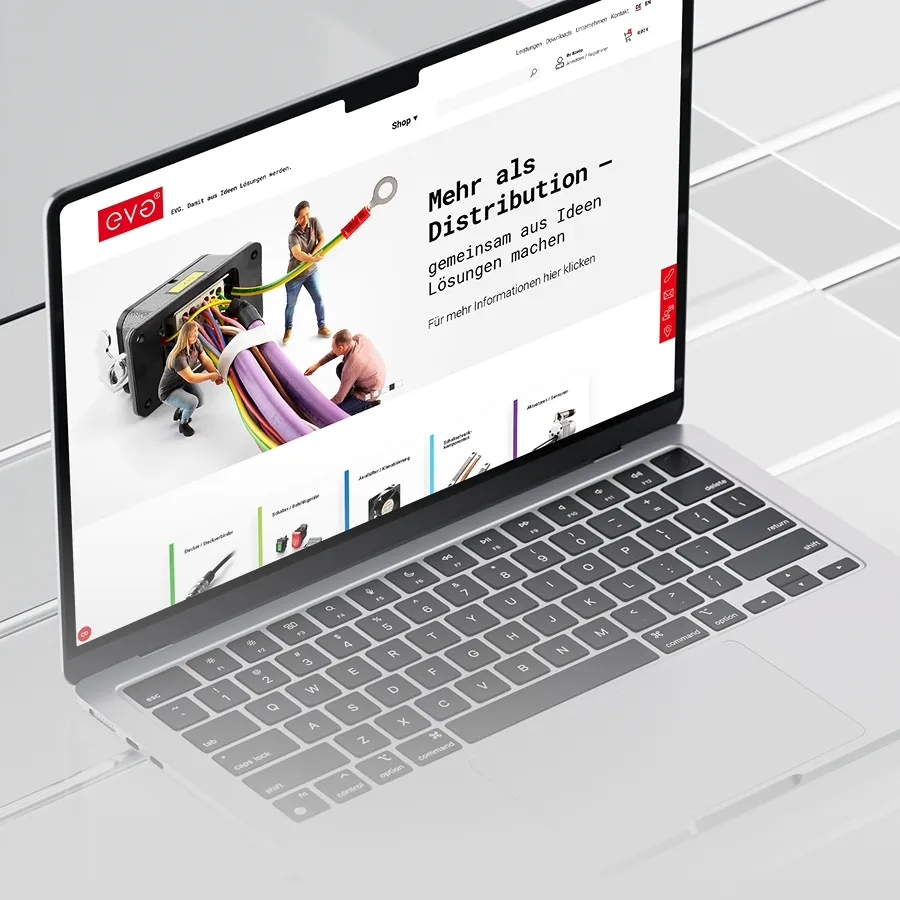 Laptop zeigt eine Webseite mit einem Bild von drei kleinen Menschen, die große farbige Kabel an einen Anschluss stecken, und dem Text ‚Mehr als Distribution – gemeinsam aus Ideen Lösungen machen‘.