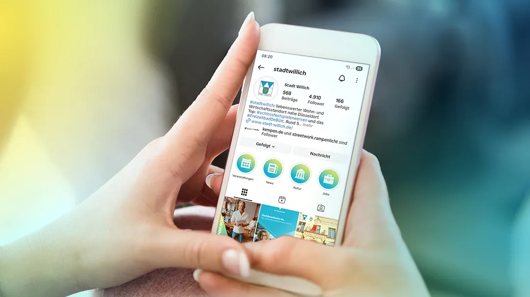Hold hands on a smartphone with the Instagram profile of the city of Willich, showing posts, followers and categories such as events, news, culture and jobs.