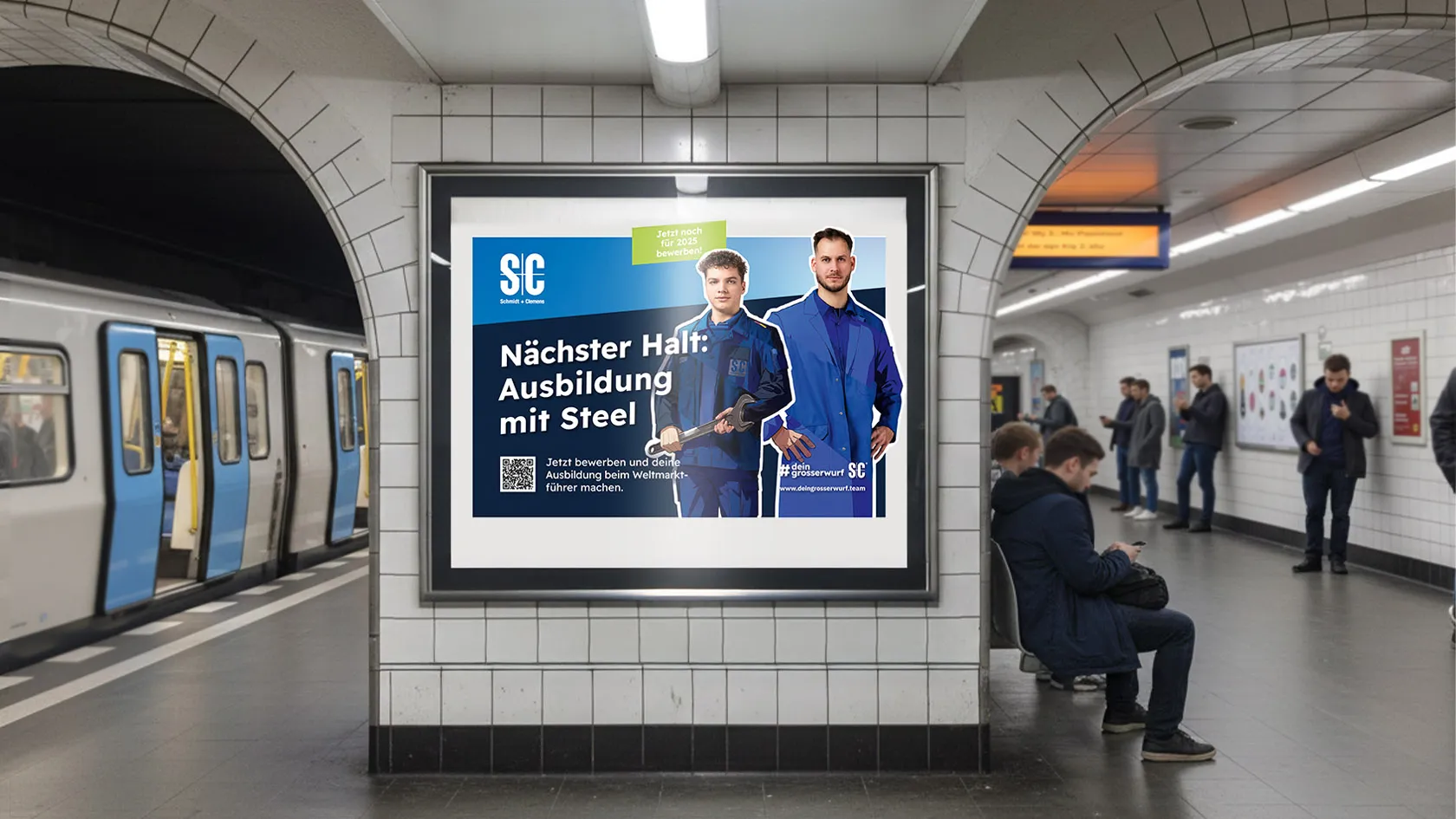 Werbeplakat in einer U-Bahn-Station zeigt zwei Männer in blauen Arbeitsjacken mit dem Text 'Nächster Halt: Ausbildung mit Steel'.