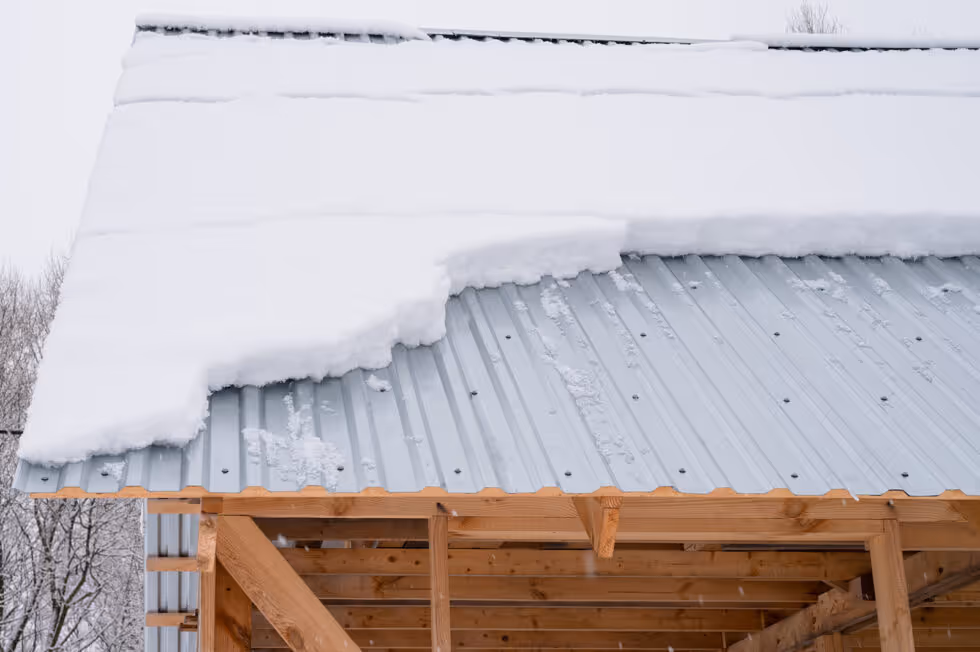 A snow covered roof with a large snow bank on the side.