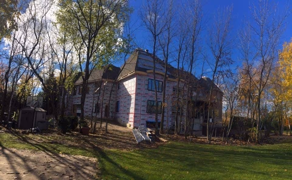 A house under construction with a blue roof and white siding.