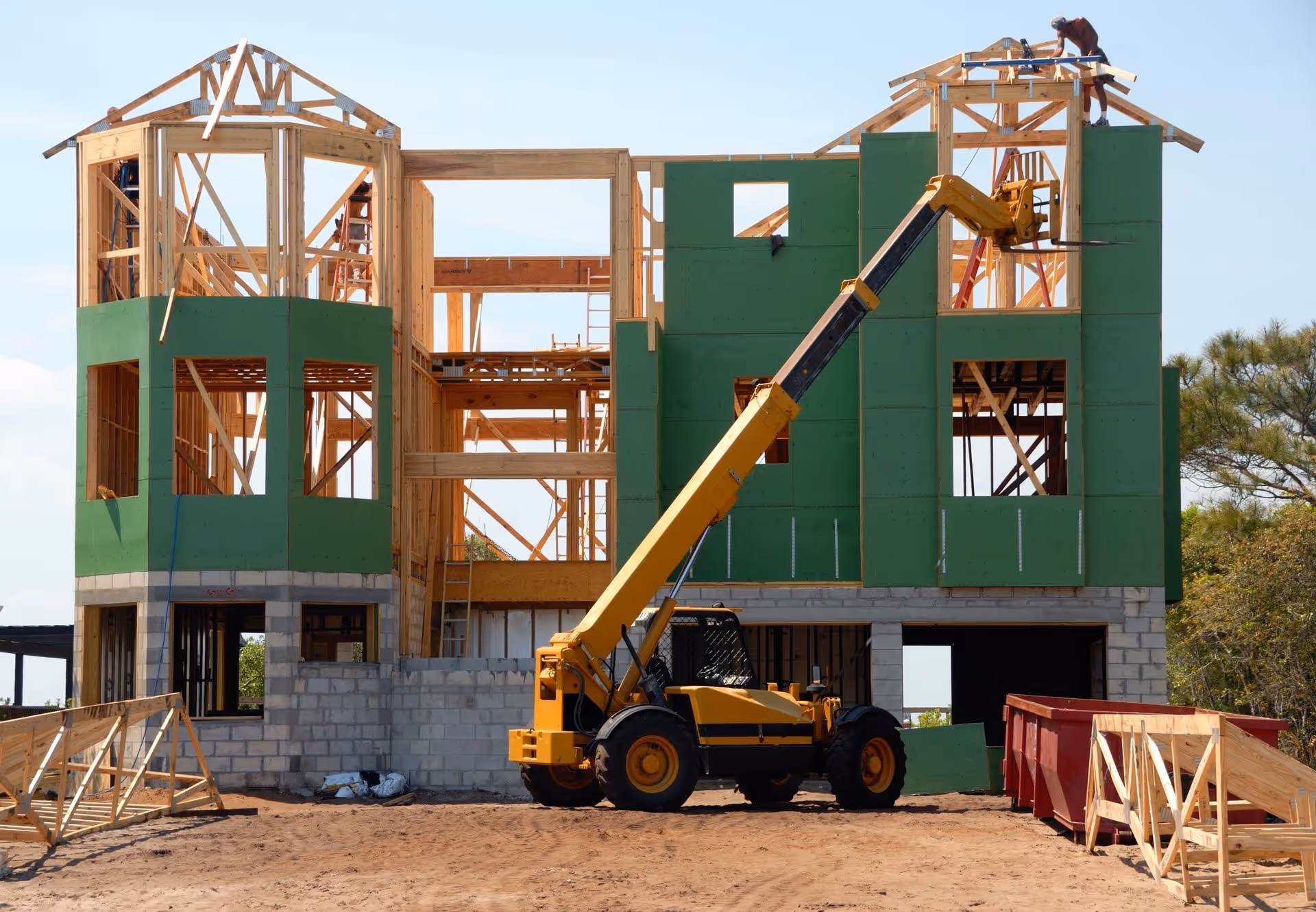 A yellow crane is parked in front of a building under construction.
