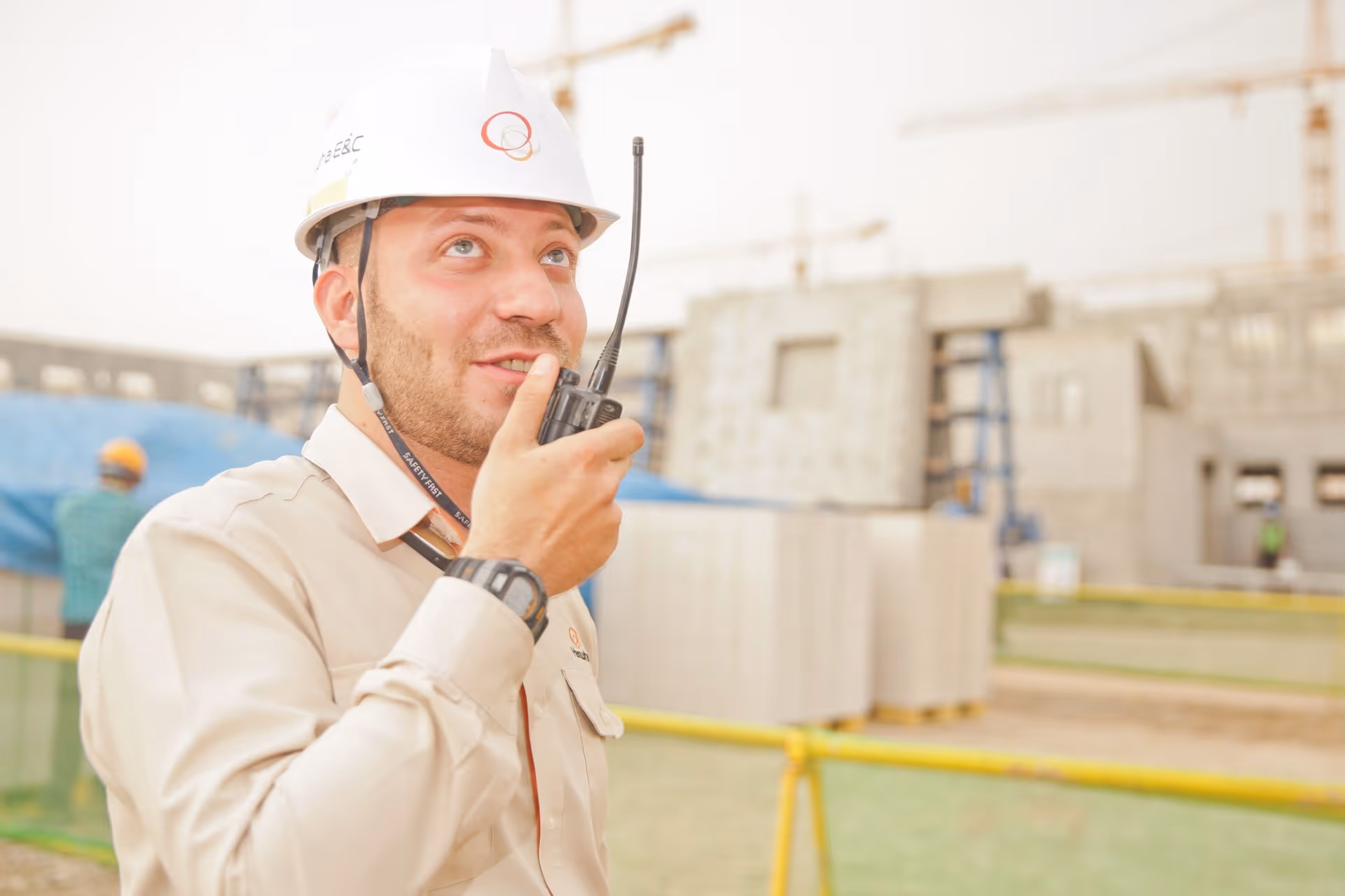 A man wearing a white helmet and holding a radio.