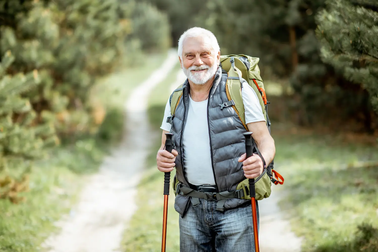 Active older man smiling with hiking poles outside.