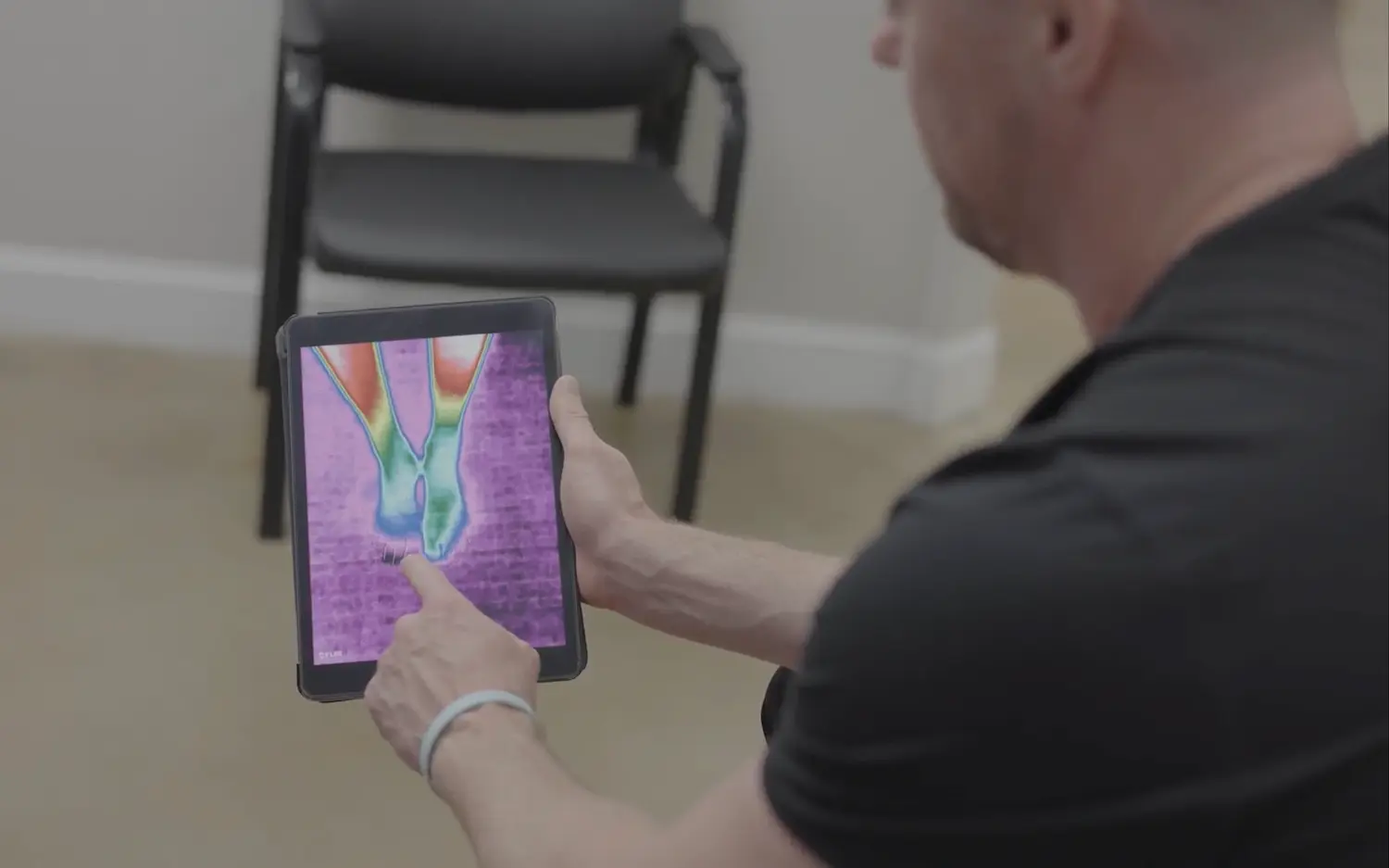Healthcare professional using a thermal imaging device on a patient’s legs to detect inflammation or injury.