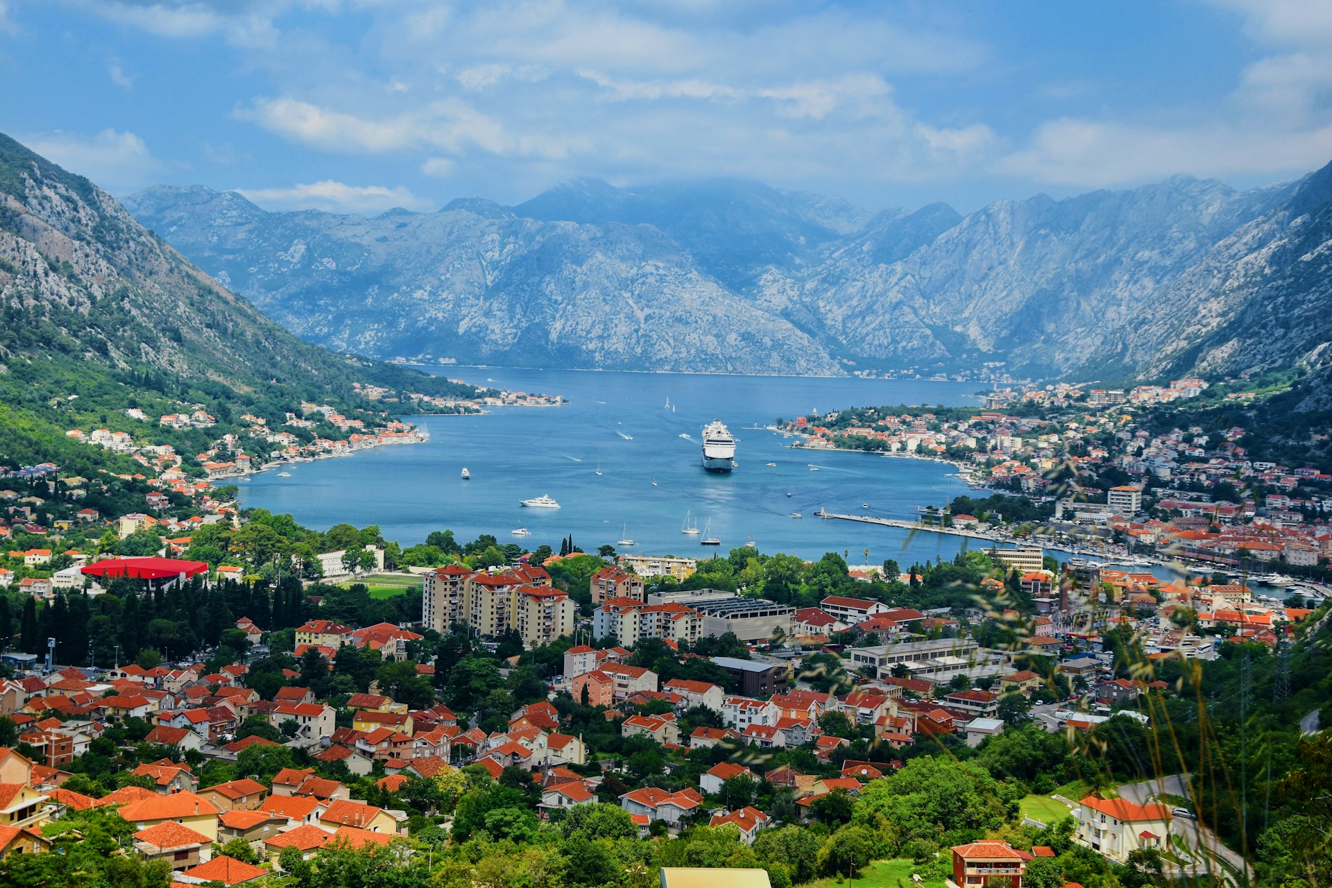 Scenic view of the Bay of Kotor, Montenegro, featuring mountains and calm blue waters under a clear sky.