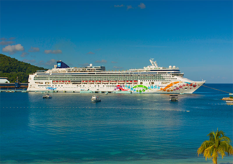 Norwegian Pearl cruise ship sailing on the open ocean under a clear blue sky