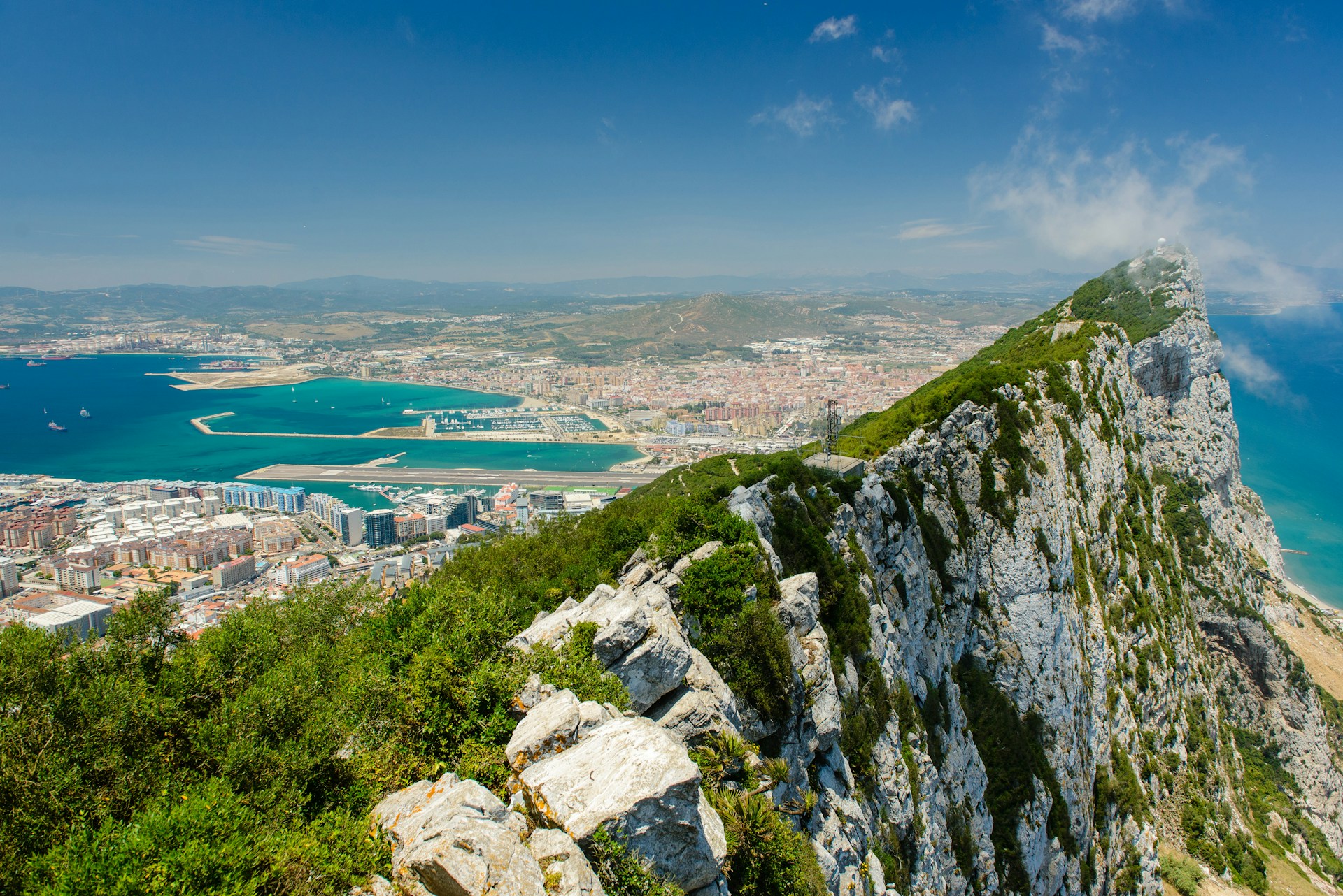 Panoramic view from the top of Gibraltar, showcasing the coastline and the Mediterranean Sea under a clear blue sky.