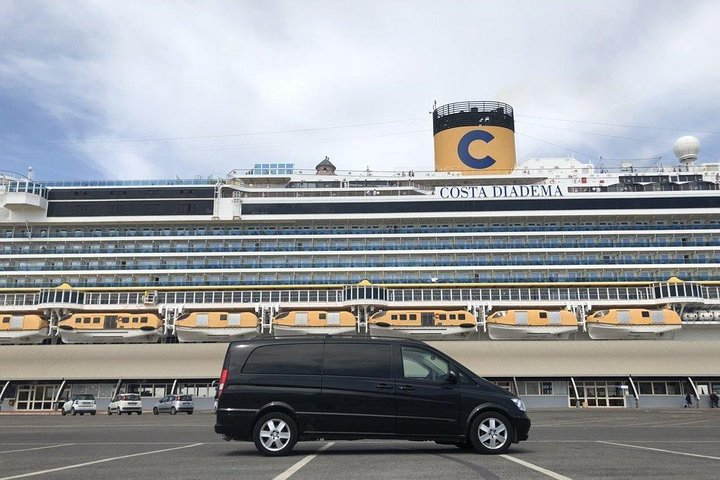 A black van parked in front of a cruise ship at the Civitavecchia cruise port near Rome.