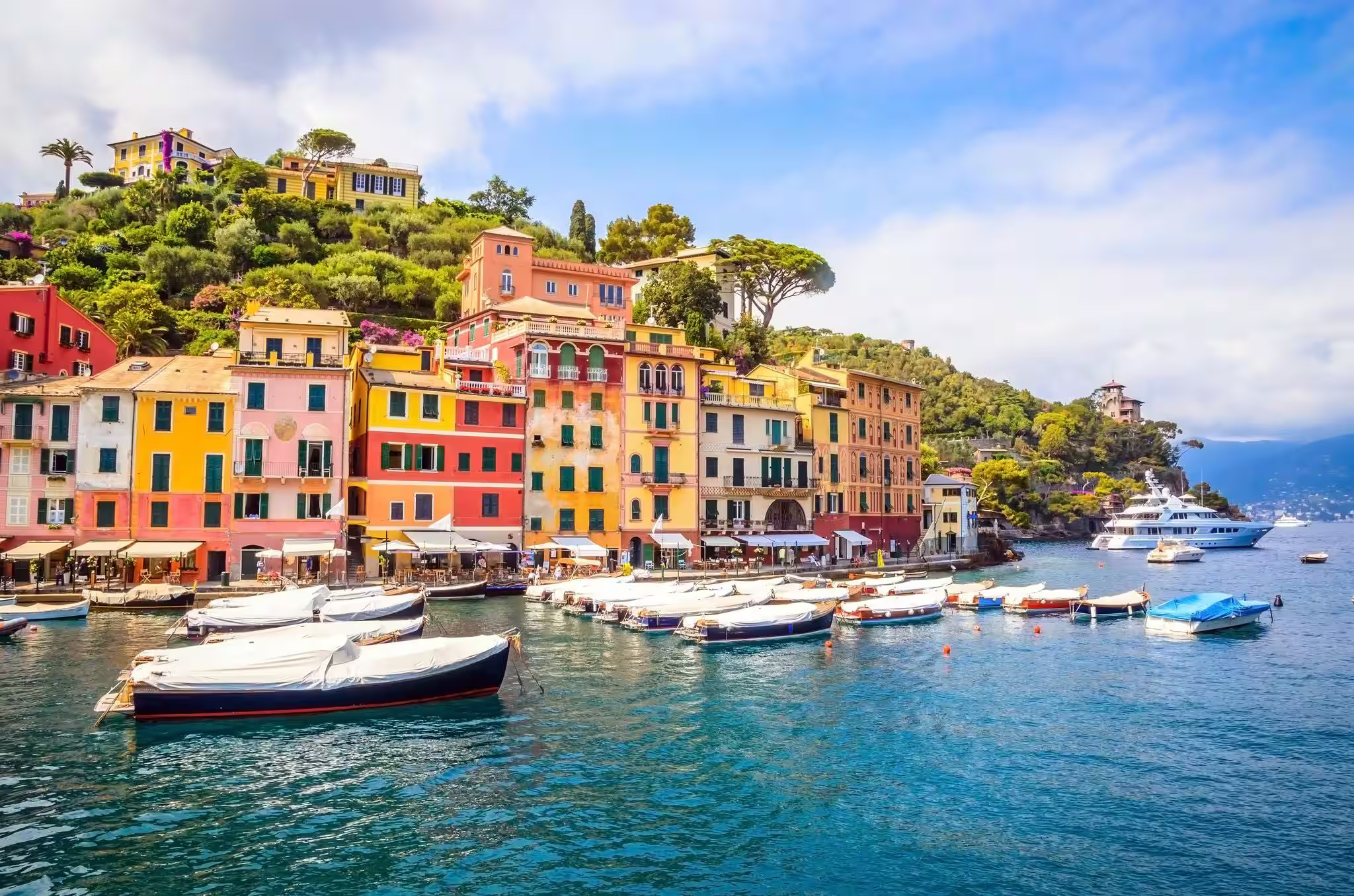 Colorful houses line the shore of Manarola, an Italian island, with vibrant facades against a backdrop of blue water.