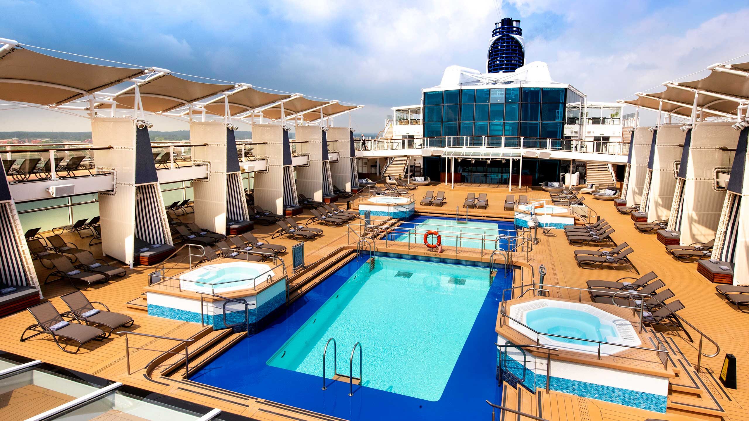 Celebrity Silhouette pool deck featuring lounge chairs, umbrellas, and a sparkling pool under a clear blue sky.