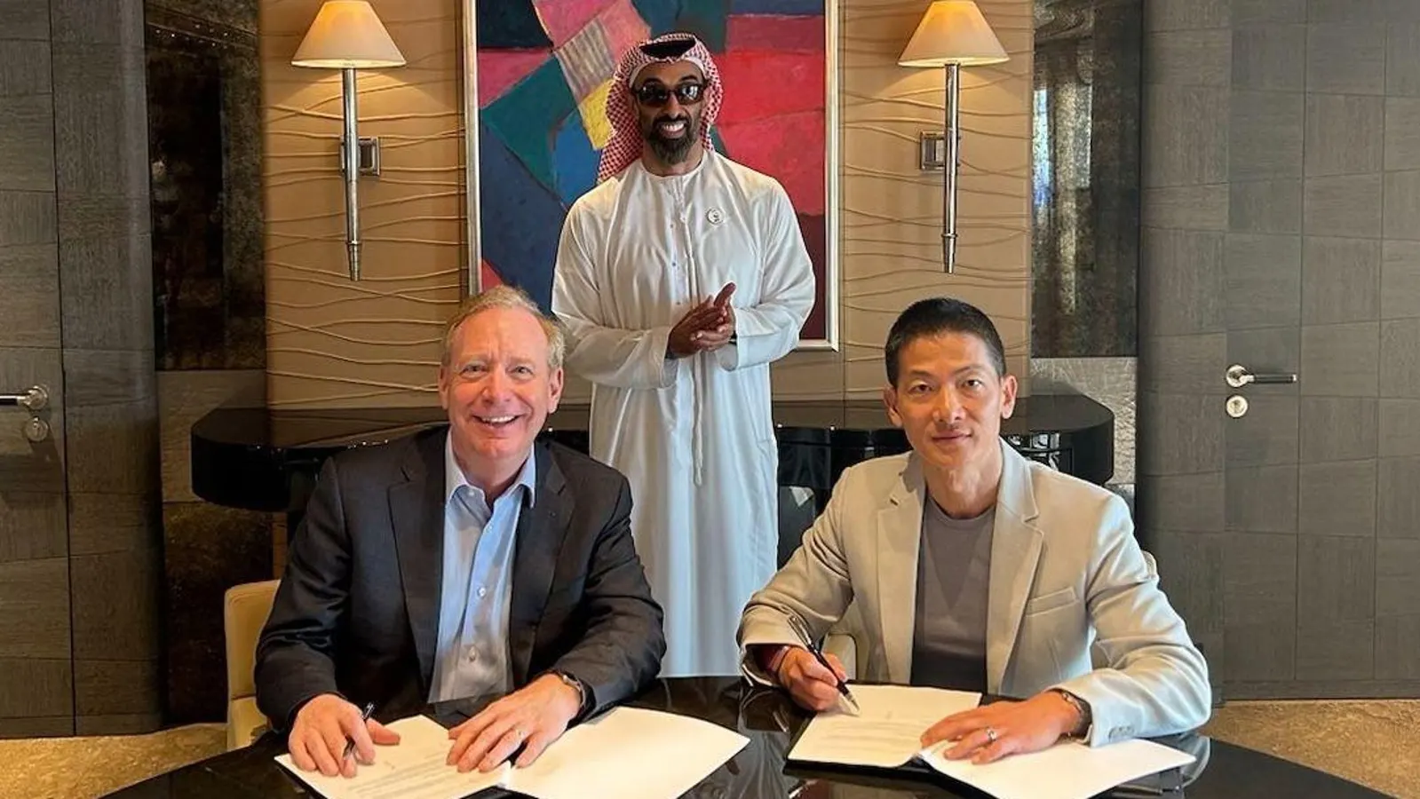 Brad Smith and Peng Xiao signing partnership agreement with UAE official standing behind, modern office background