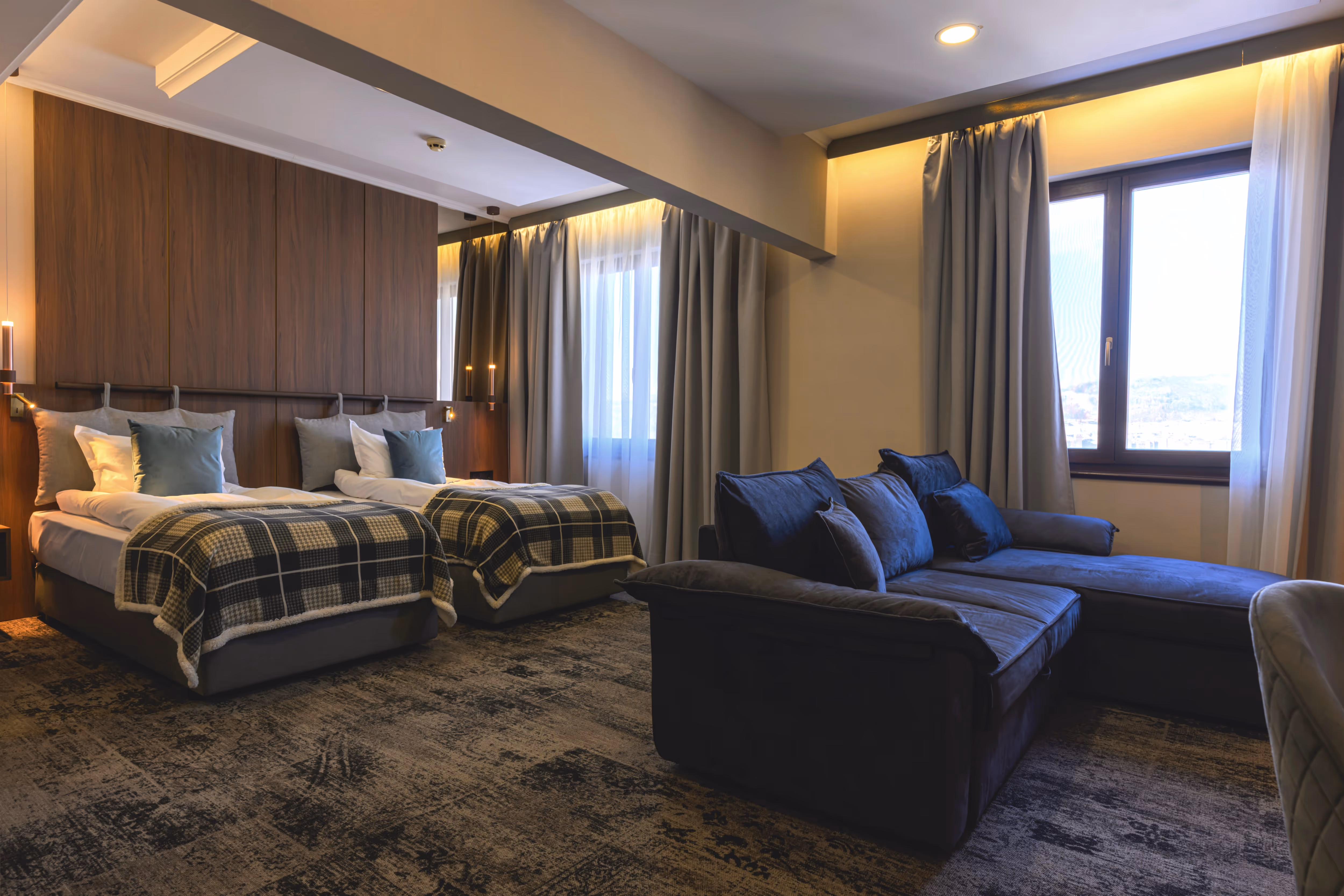 Елегантна двойна стая с изглед към Царевец, обзаведена с комфортно двойно легло, декоративни възглавници в черно, бяло и лилаво, и стилна тапетирана стена с картина.