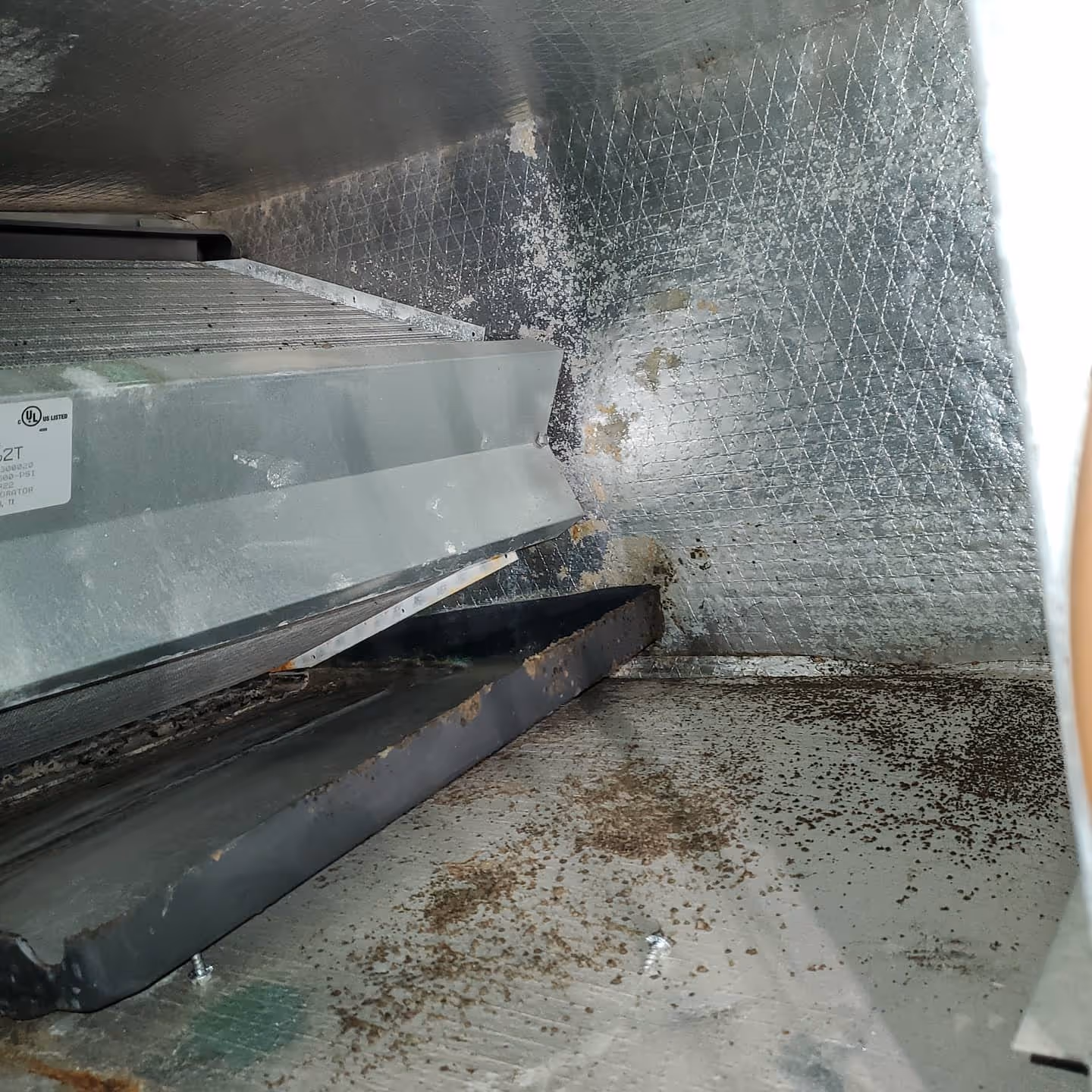 Dirty industrial equipment corner with metal surfaces and scattered debris