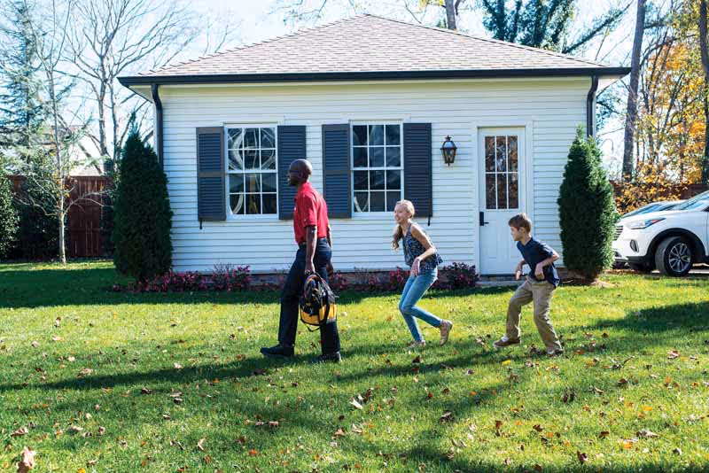 Family playing together on grassy lawn in front of white house
