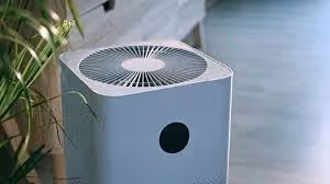 Modern white air purifier with circular fan design near green plant