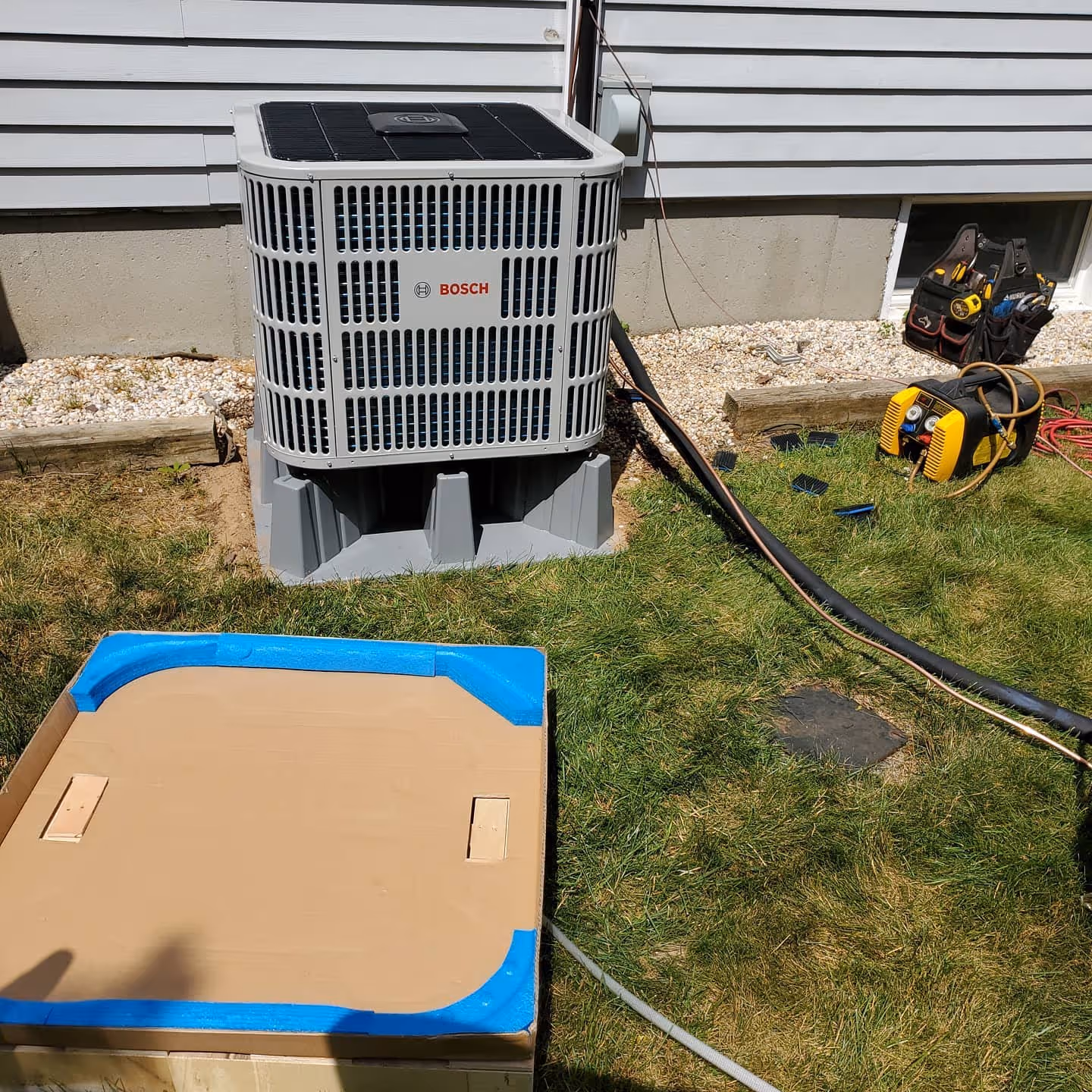 Bosch air conditioning unit with tools and cardboard box on grass